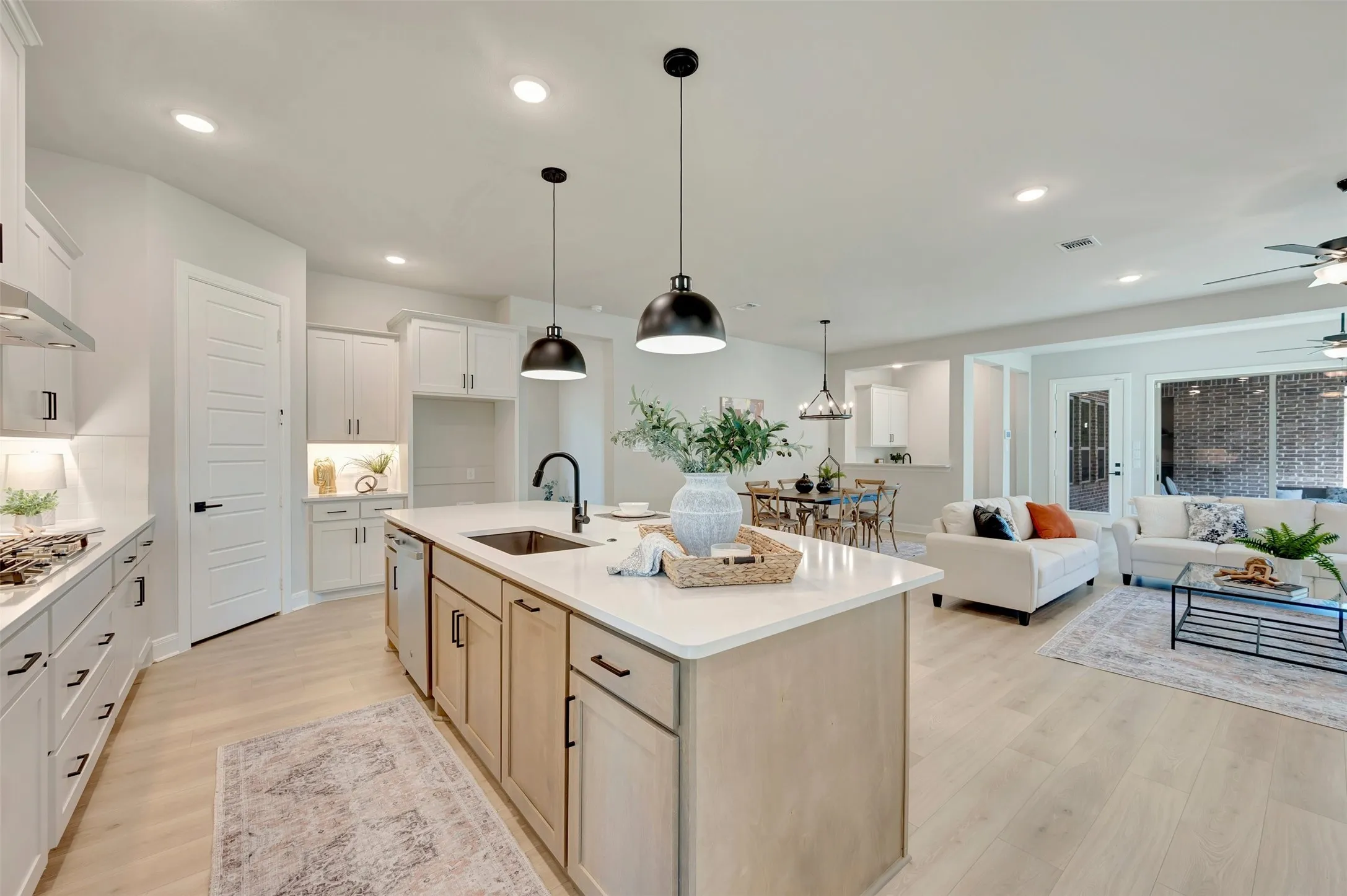 Open-concept living space with light wood-finish flooring, recessed lighting, and white cabinetry