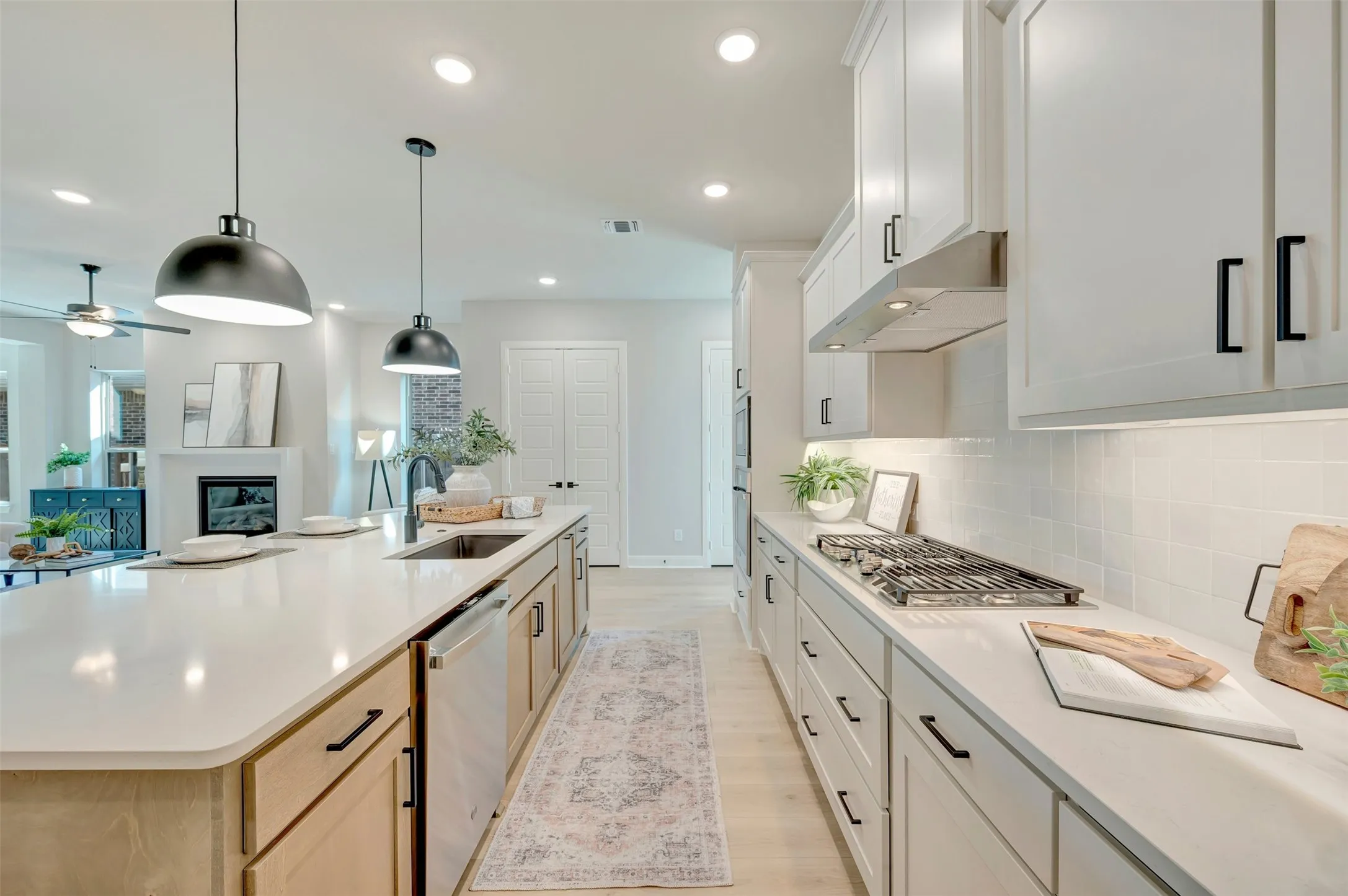 Expansive kitchen island with an undermount sink, pendant lighting, and light wood-finish cabinetry