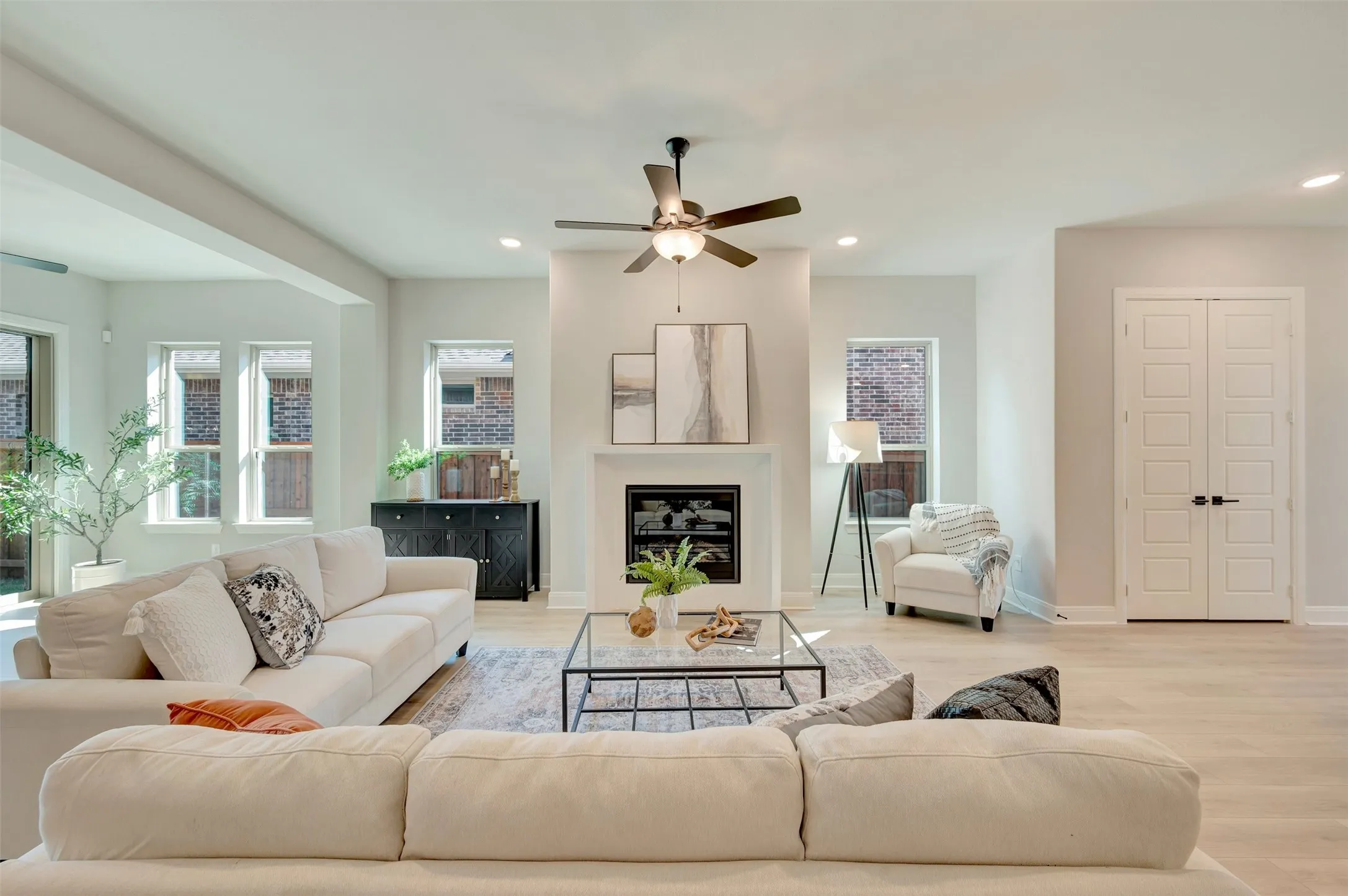 Spacious living area featuring a fireplace with a white mantel, light wood-finish flooring, a ceiling fan, and recessed lighting