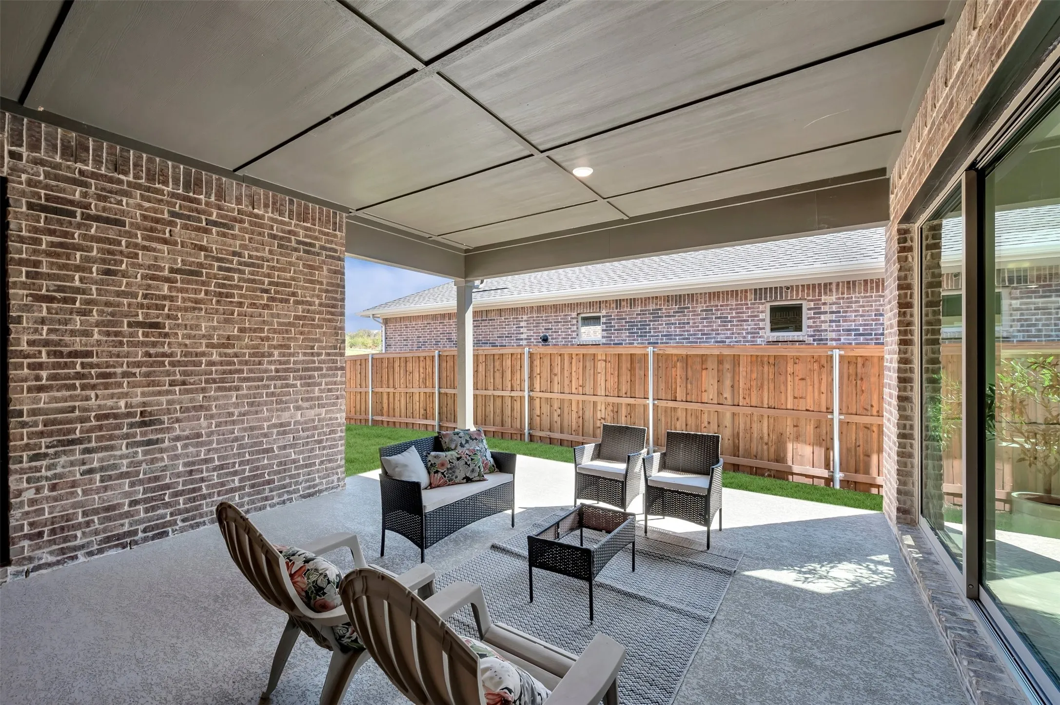 Covered patio featuring a concrete surface, brick exterior wall, and sliding glass door