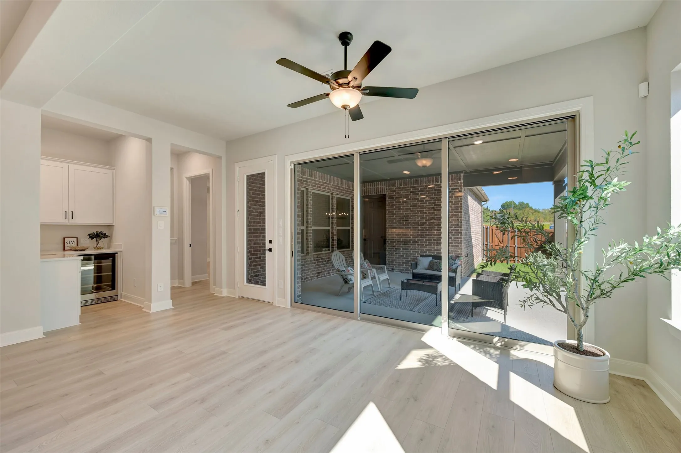 Light wood-finish flooring with a ceiling fan, built-in cabinetry, and a beverage cooler