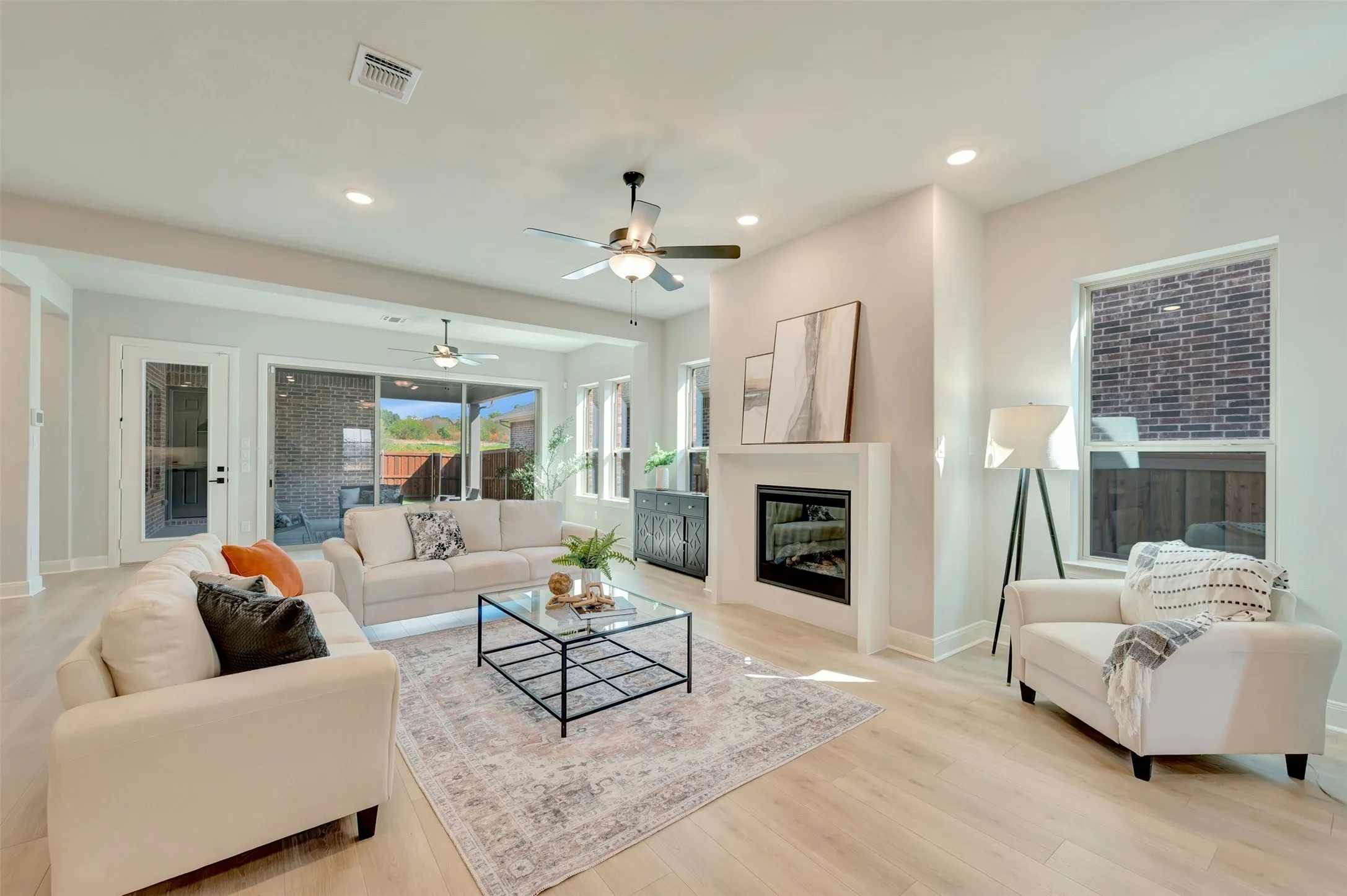 Living area with wood-finish flooring, recessed lighting, ceiling fan, fireplace with mantel, and sliding glass doors to outdoor space