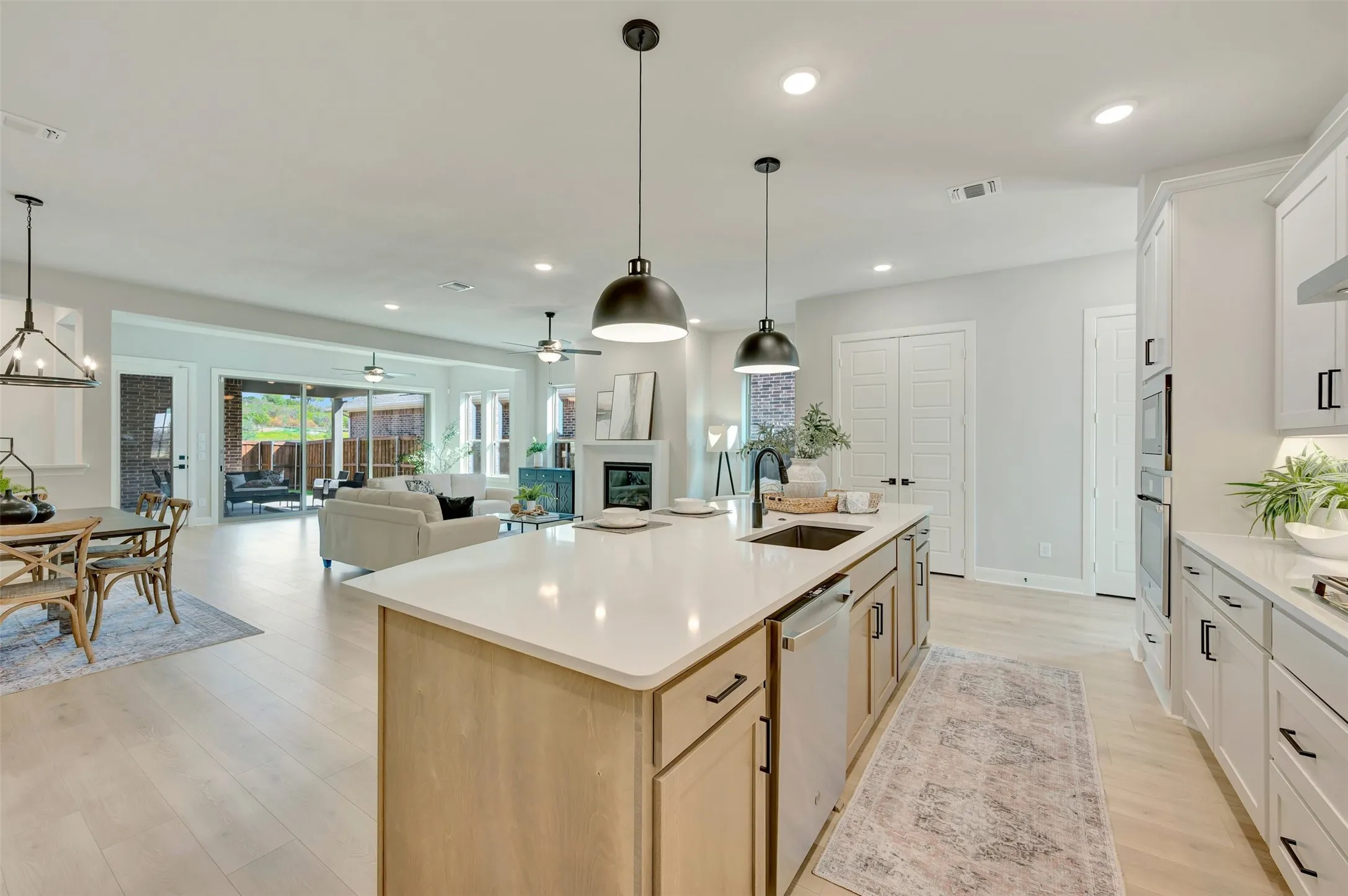 Kitchen island with an undermount sink, pendant lighting, and light finish cabinetry