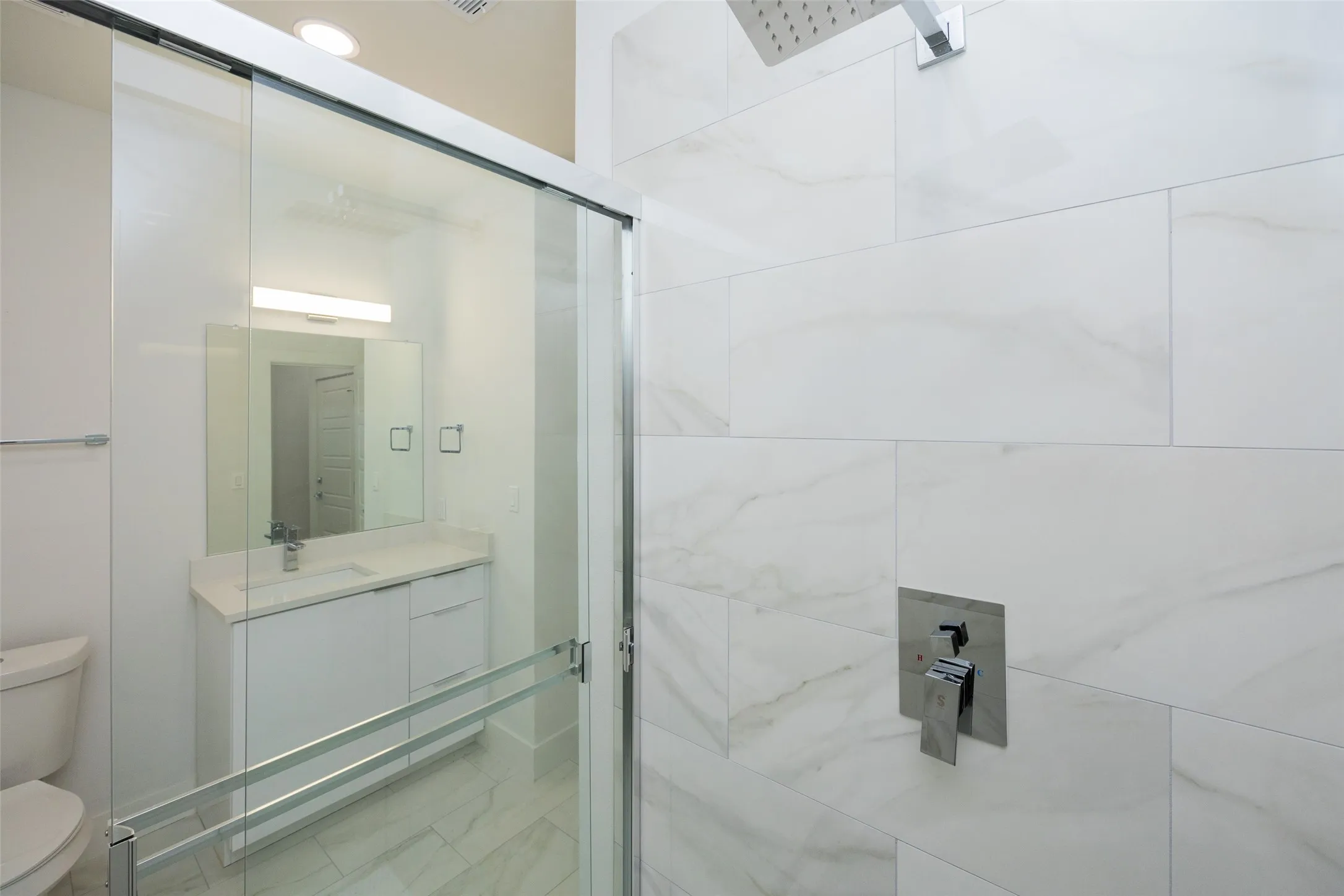 Walk-in shower with clear glass enclosure and rainfall showerhead