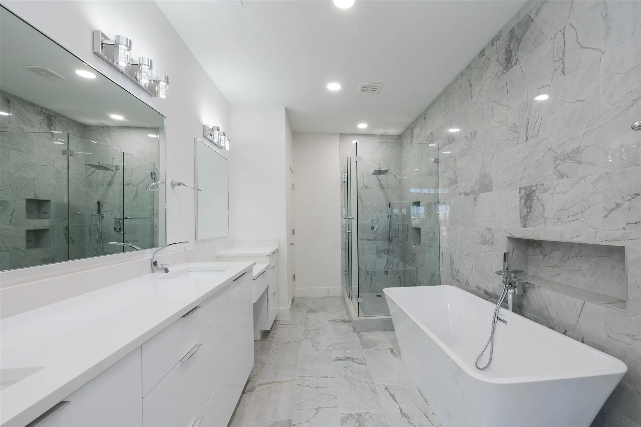 Spacious bathroom featuring a dual vanity, large wall mirror, recessed lighting, and a freestanding soaking tub