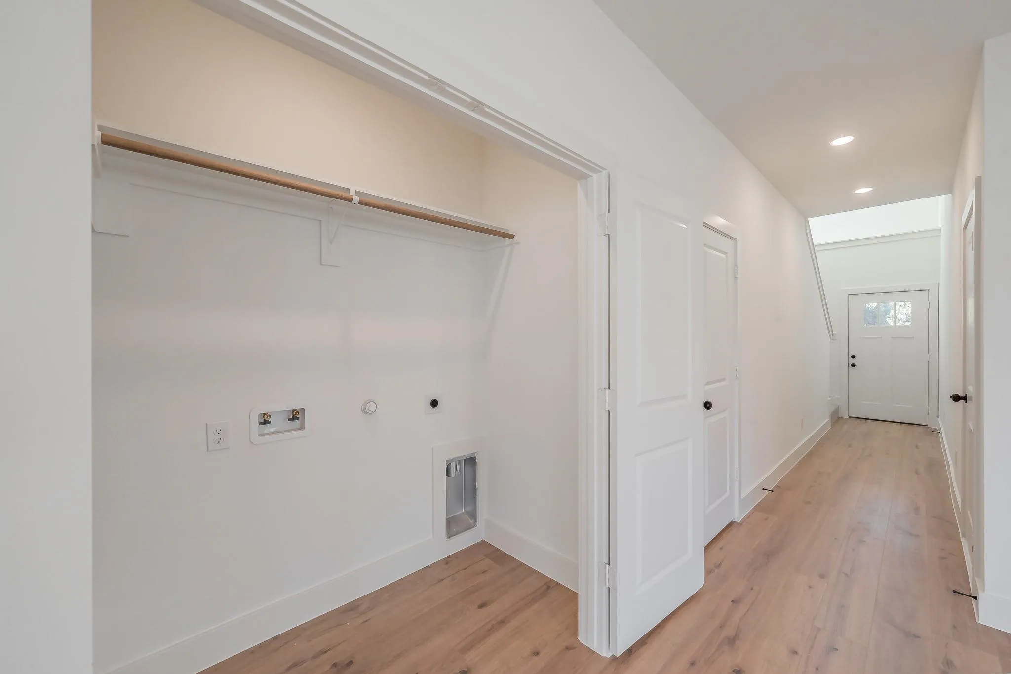 Hallway featuring wood-finish flooring, recessed lighting, and a white paneled door