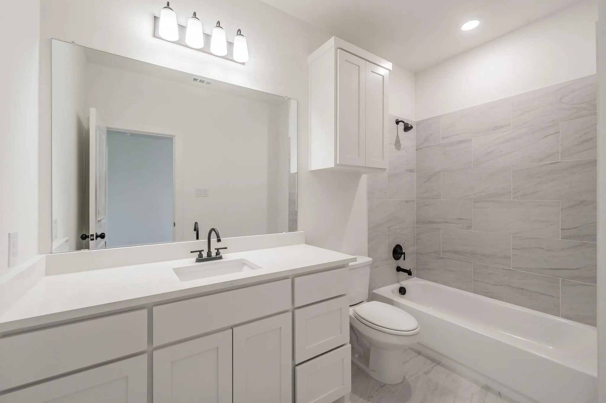 Bathroom featuring a white vanity with an integrated sink, black-finish faucet, and a large wall-mounted mirror