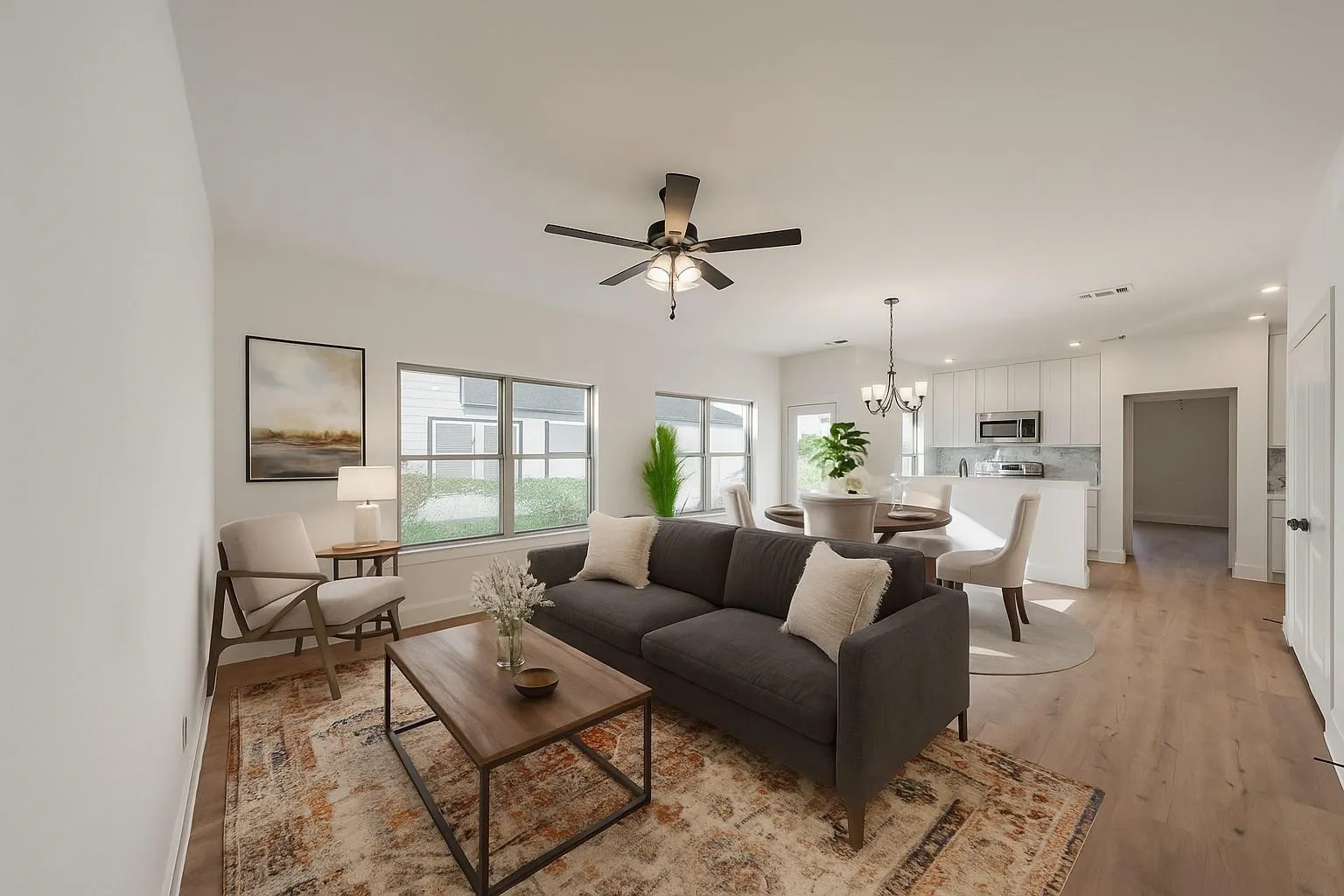 Open-concept living space featuring wood-finish flooring, recessed lighting, and multiple windows