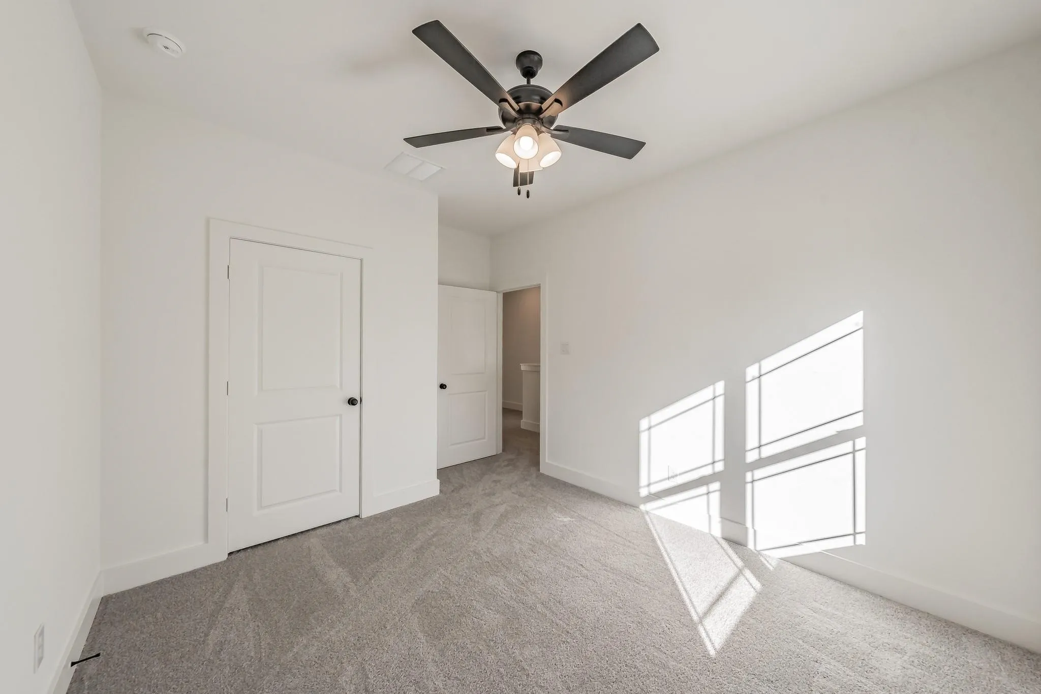 Carpeted flooring, contemporary ceiling fan with integrated lighting, white interior doors with black hardware, and recessed lighting