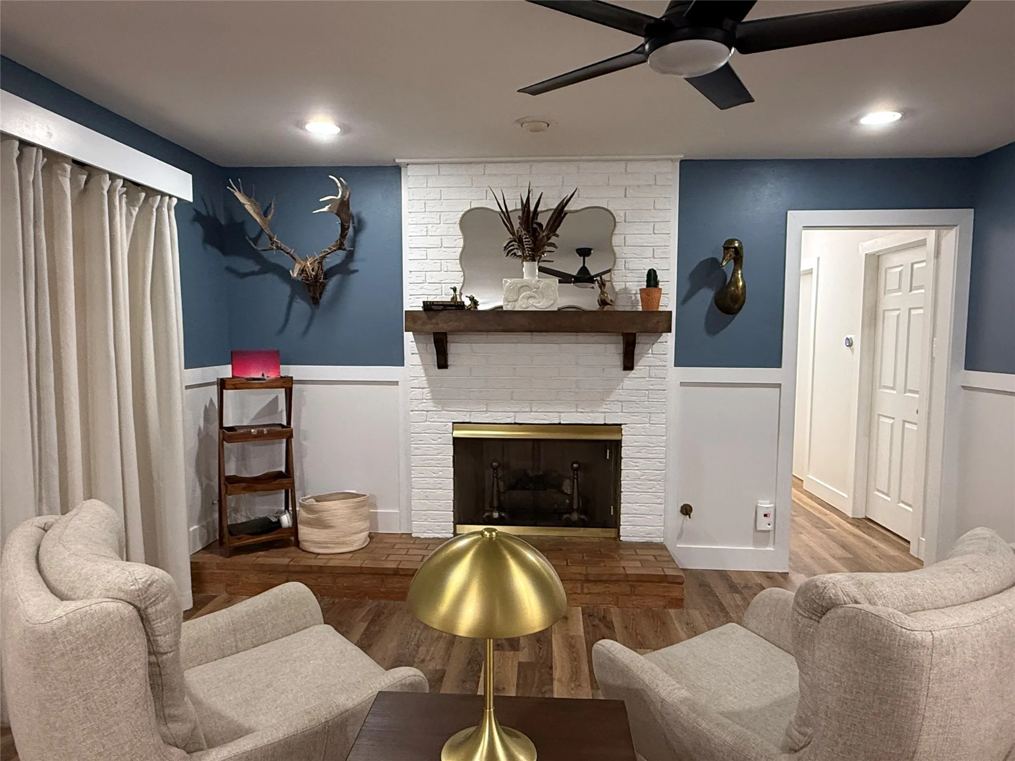 White painted brick fireplace with a wood mantel, brick hearth, and brass-tone insert