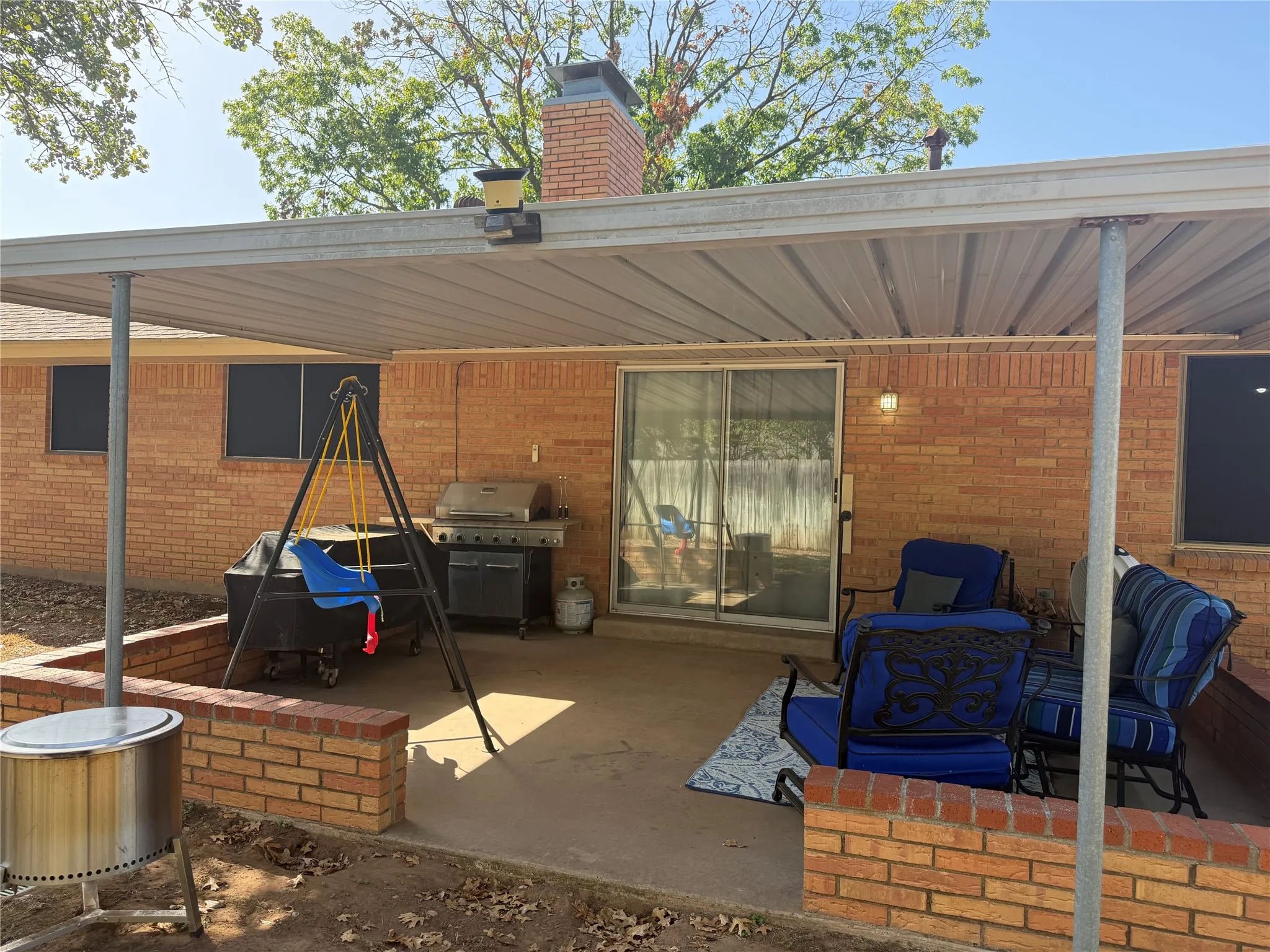 Covered patio with a concrete slab, brick exterior, and sliding glass door access