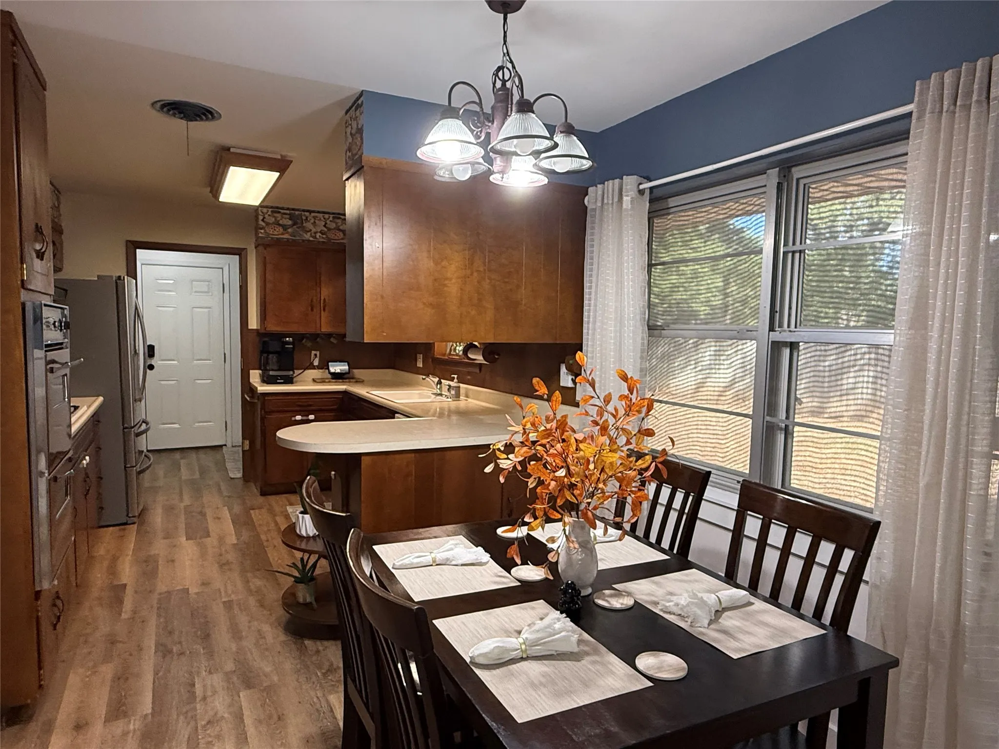 Kitchen featuring wood Luxury Plank flooring, wood cabinetry, light-toned countertops, and stainless steel appliances
