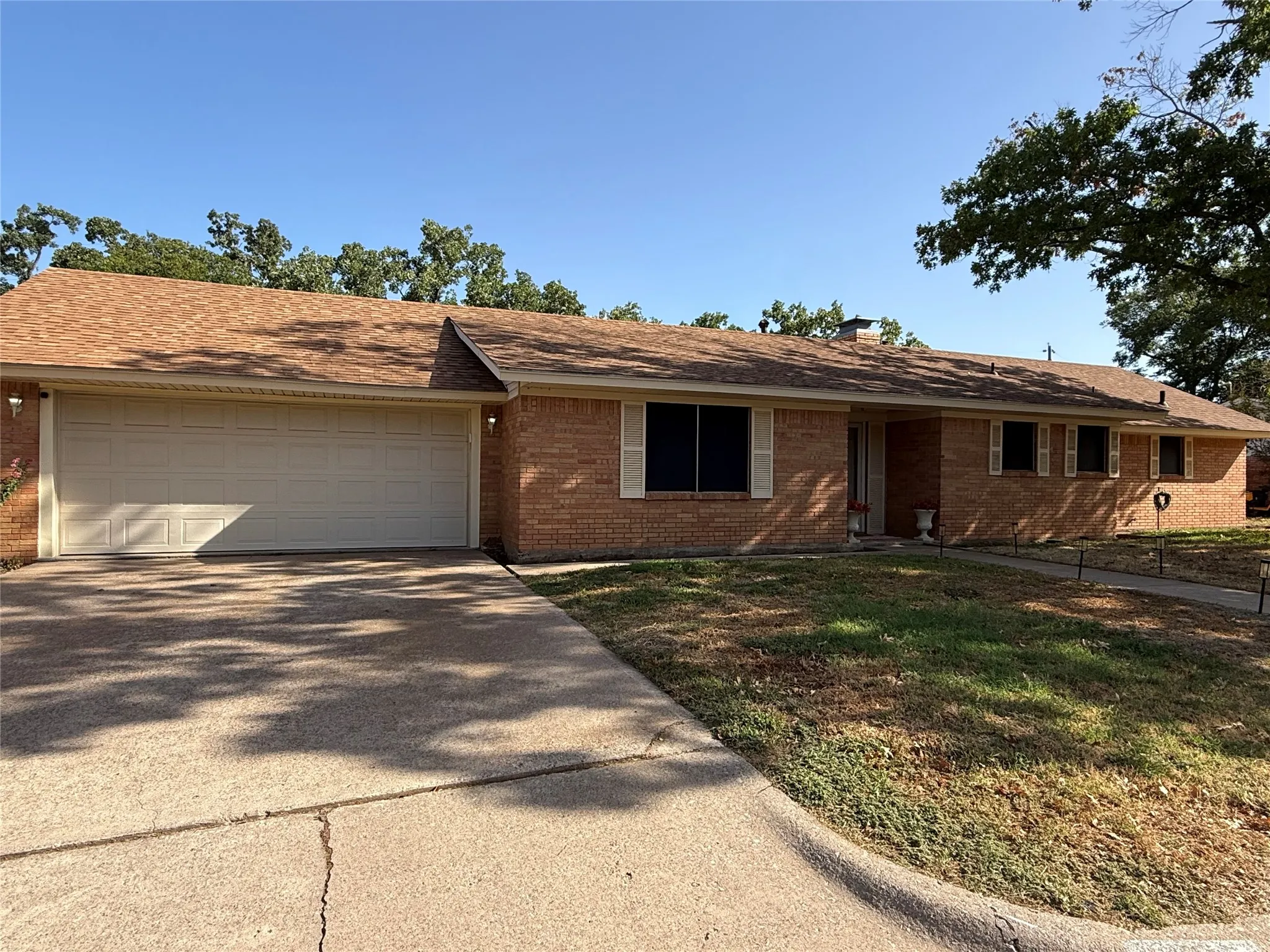 Brick exterior with an attached two-car garage, concrete driveway, and front walkway