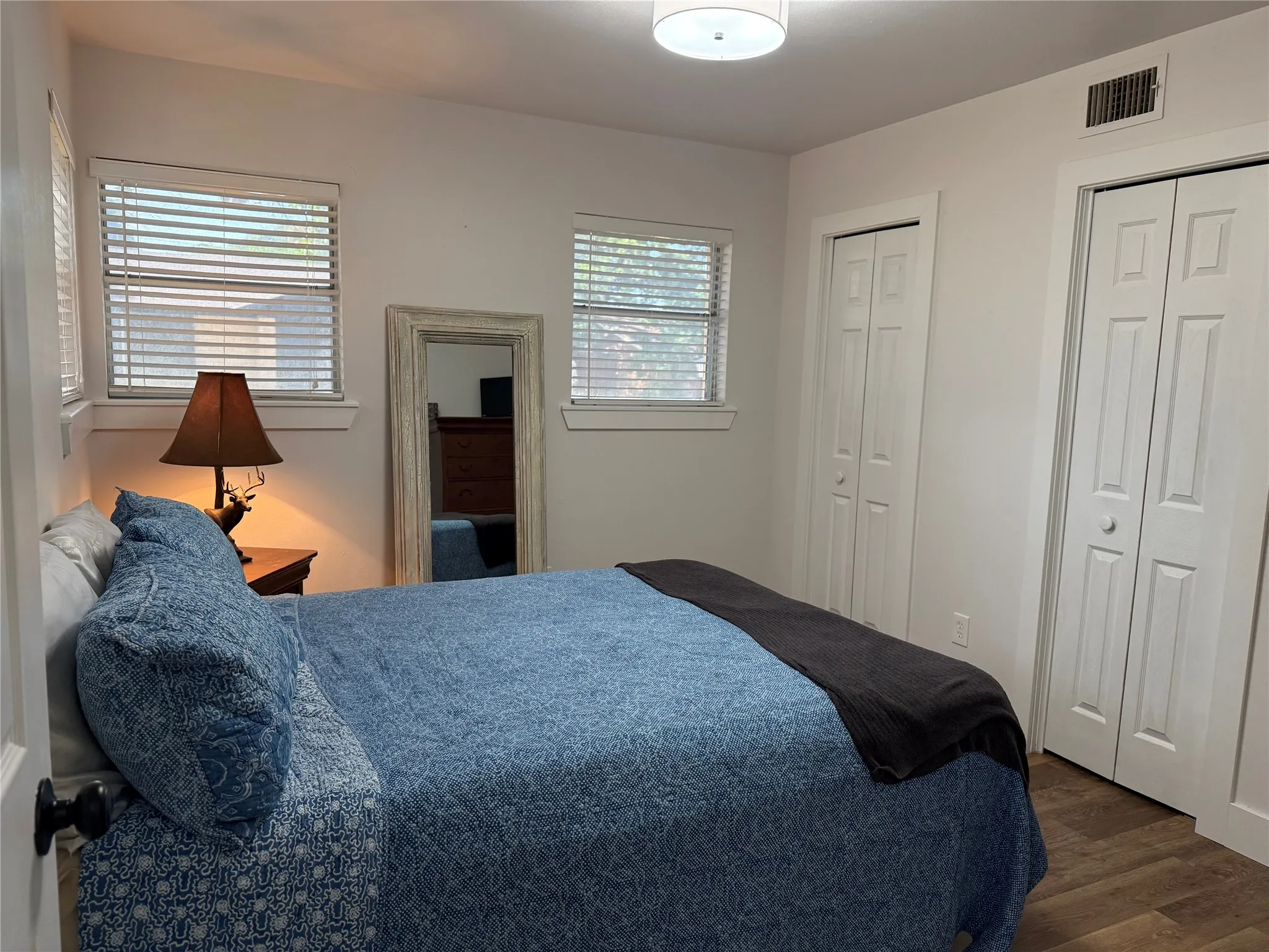 Luxury Plank flooring, two large windows with blinds, and white bi-fold closet doors
