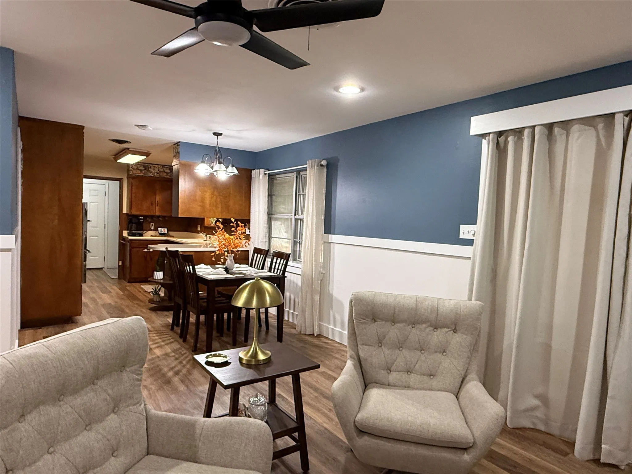 Recessed lighting, ceiling fan, wood-finish flooring, half-wall wainscoting, and a window with blinds