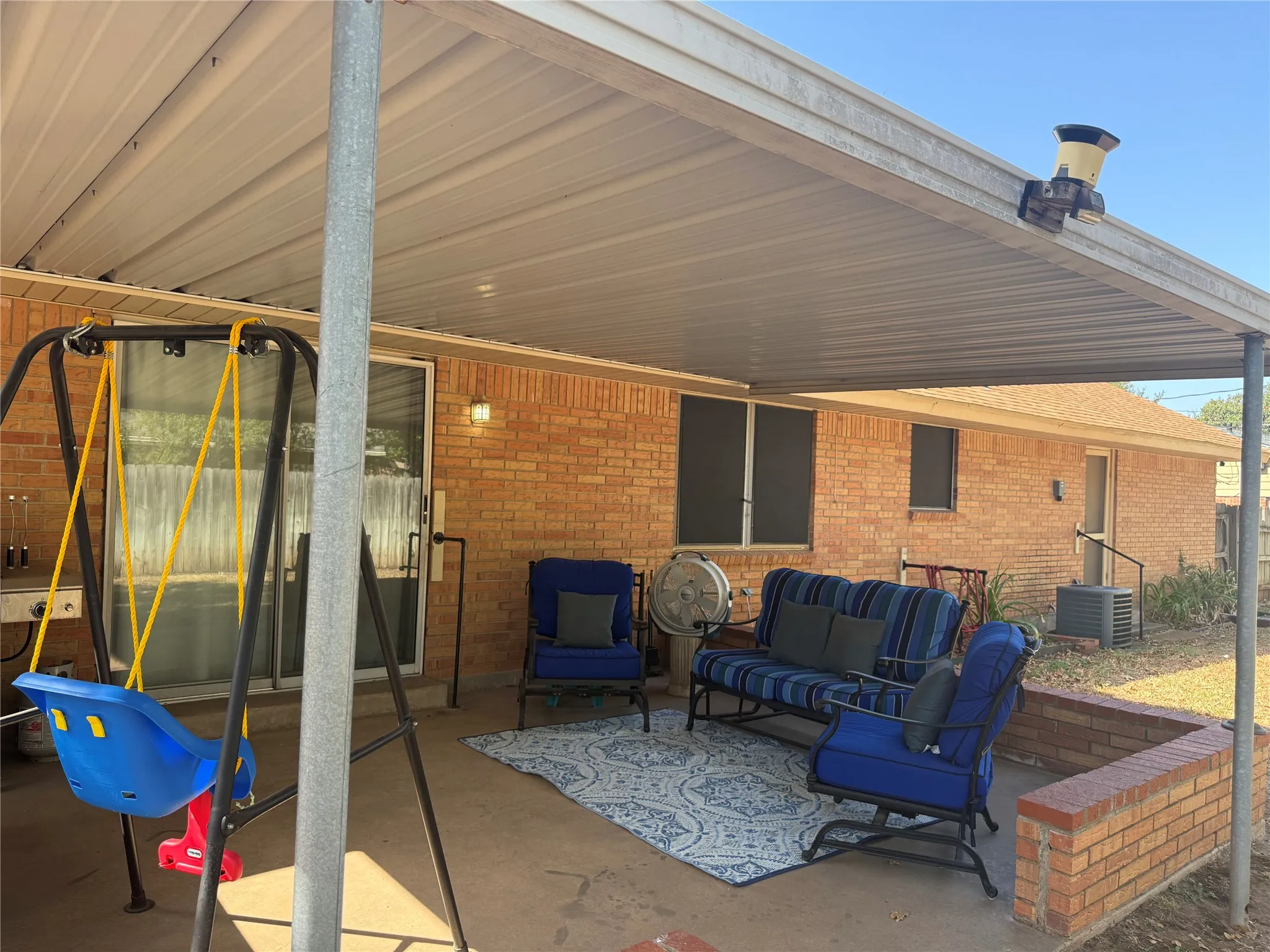 Brick exterior featuring a covered patio with a metal roof