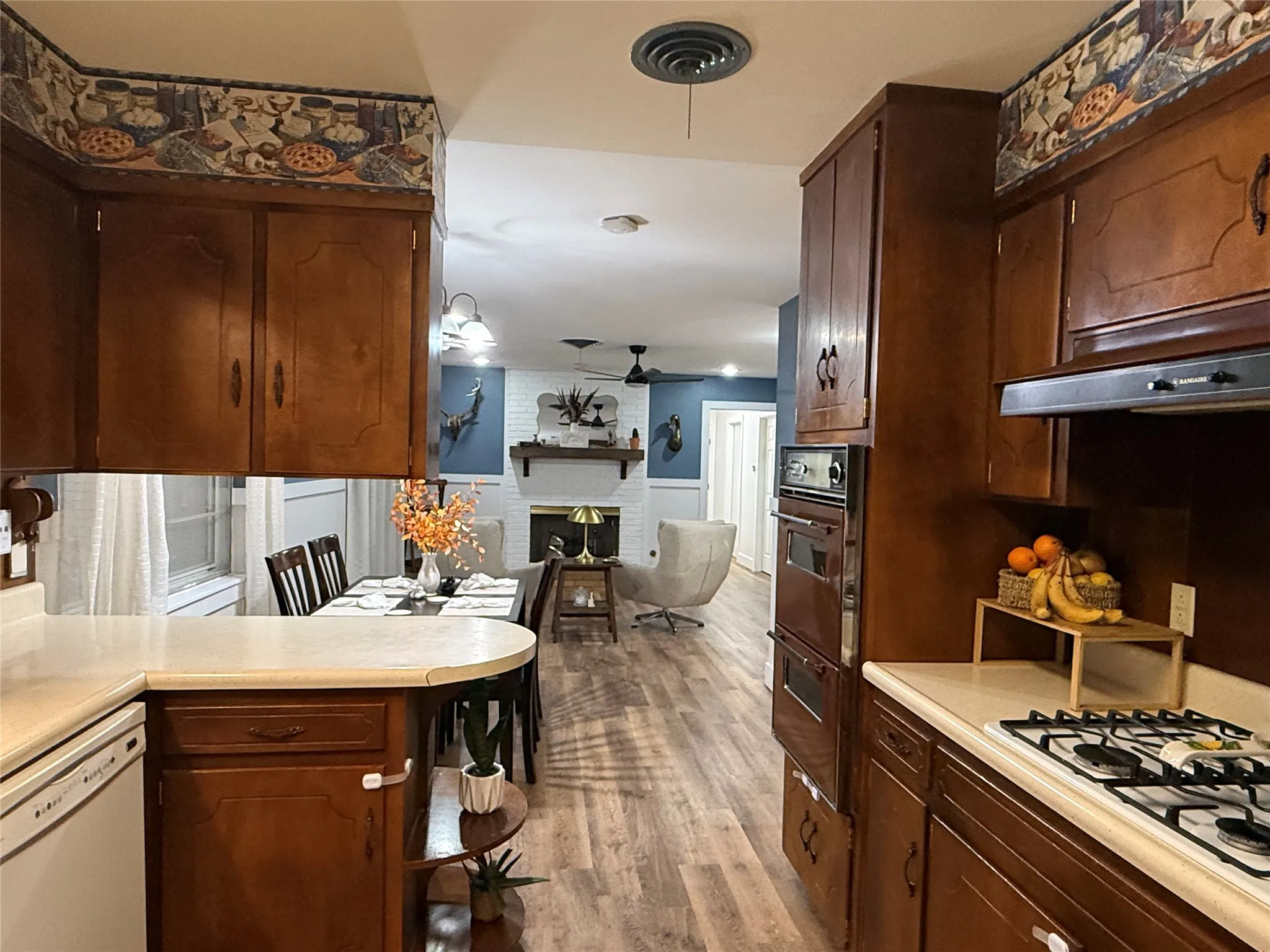 Kitchen with wood-finish cabinetry, built-in wall oven, and gas cooktop