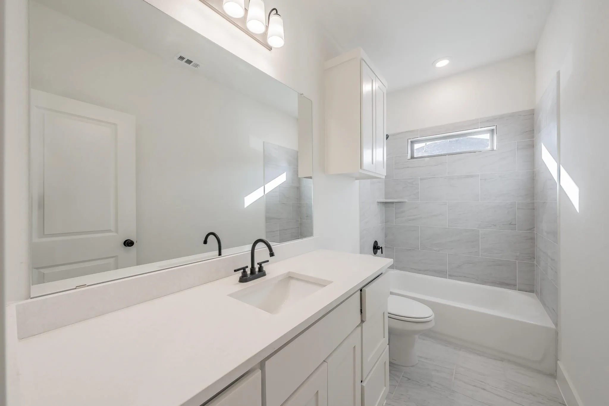 White vanity with a light-toned countertop, matte black faucet, and rectangular undermount sink
