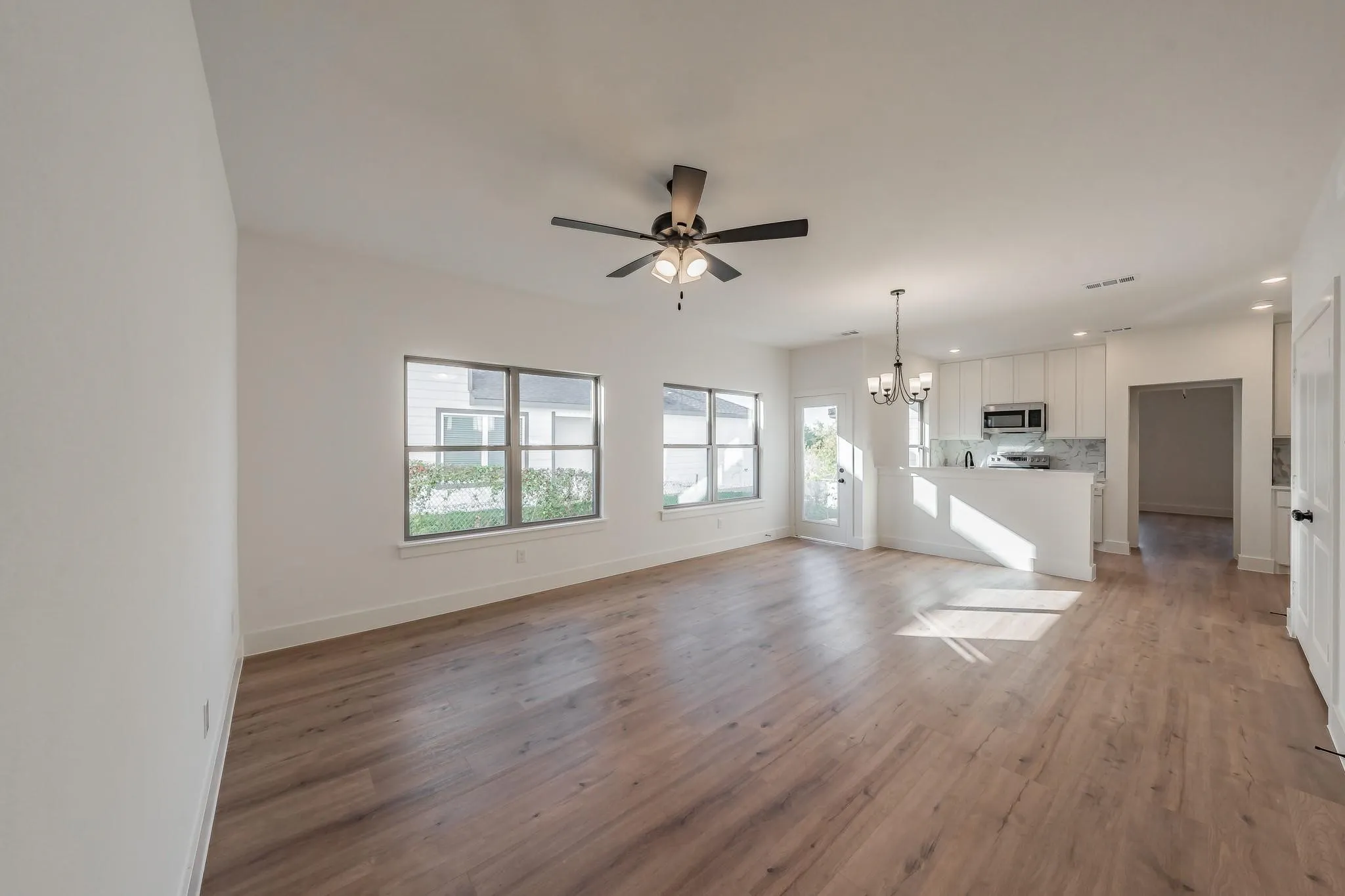 Spacious interior featuring wood-finish flooring, multiple windows, a ceiling fan, and recessed lighting