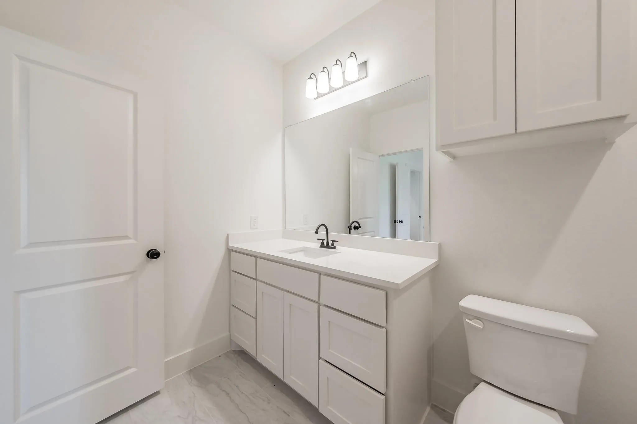 White vanity with integrated sink, expansive wall mirror, and modern light fixture