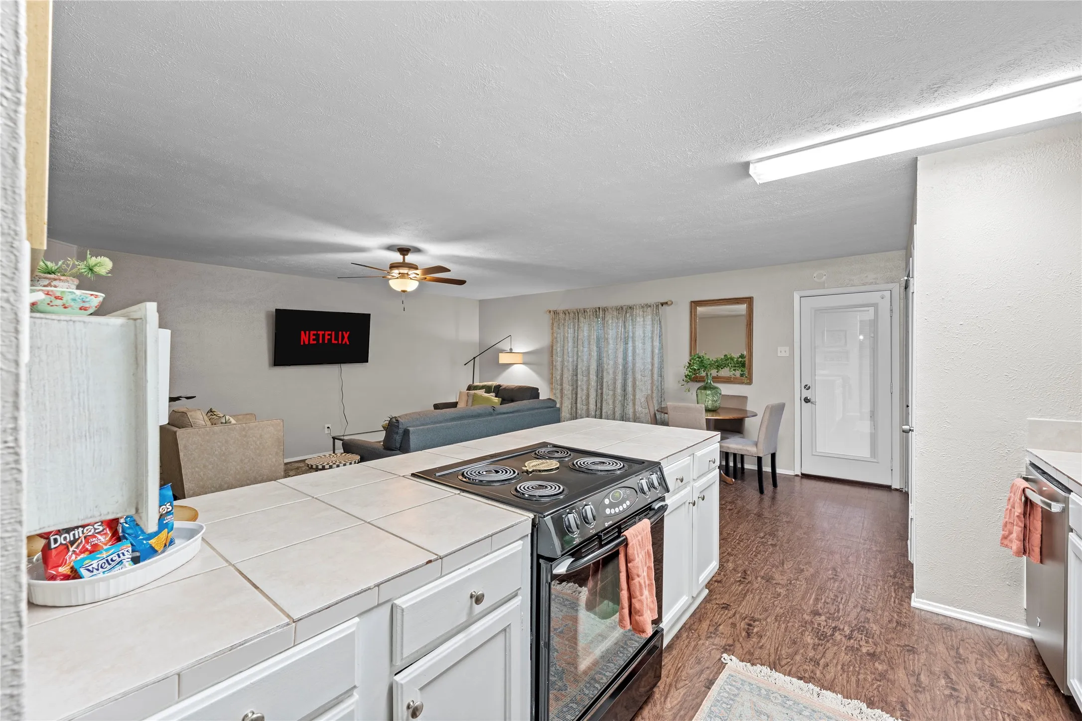 Kitchen with tile countertops, white cabinetry, and built-in electric range