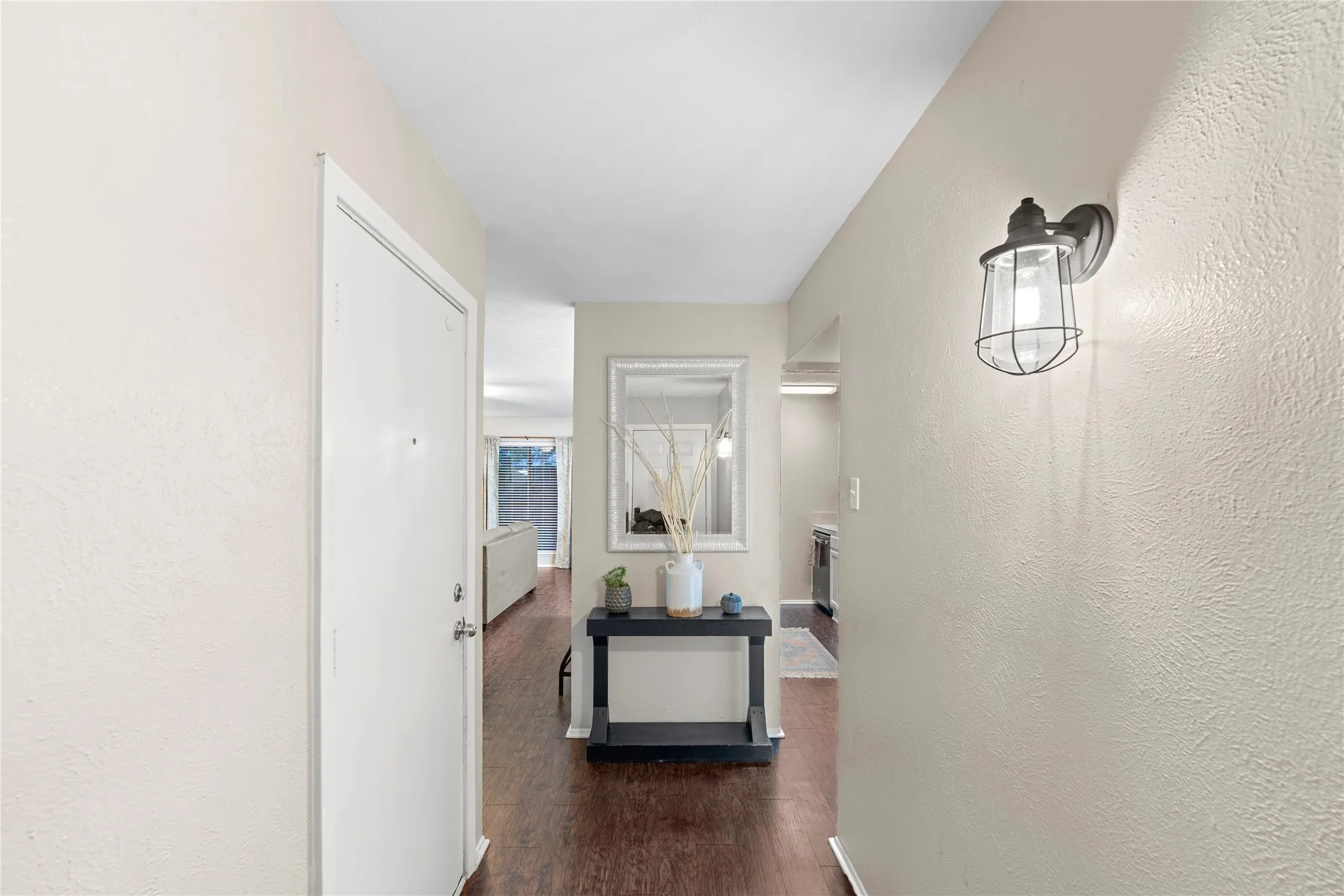 Entryway featuring a decorative wall sconce, wood-finish flooring, and a framed mirror