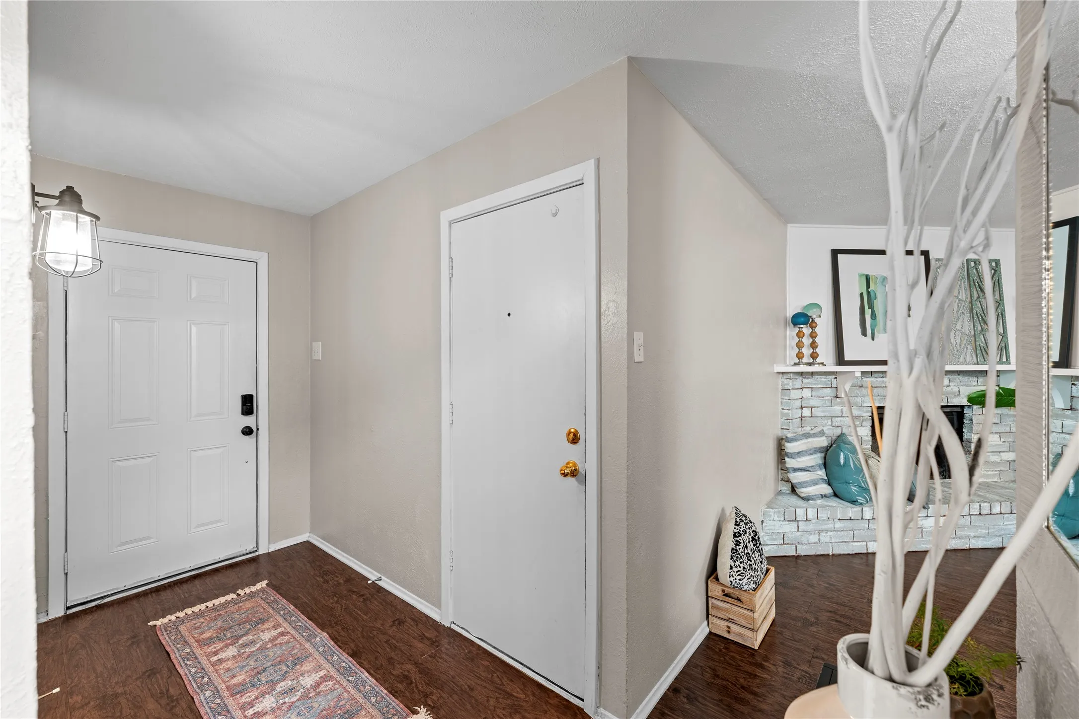 Wood-finish flooring throughout the entry, featuring a paneled entry door with dark hardware and a caged sconce light fixture