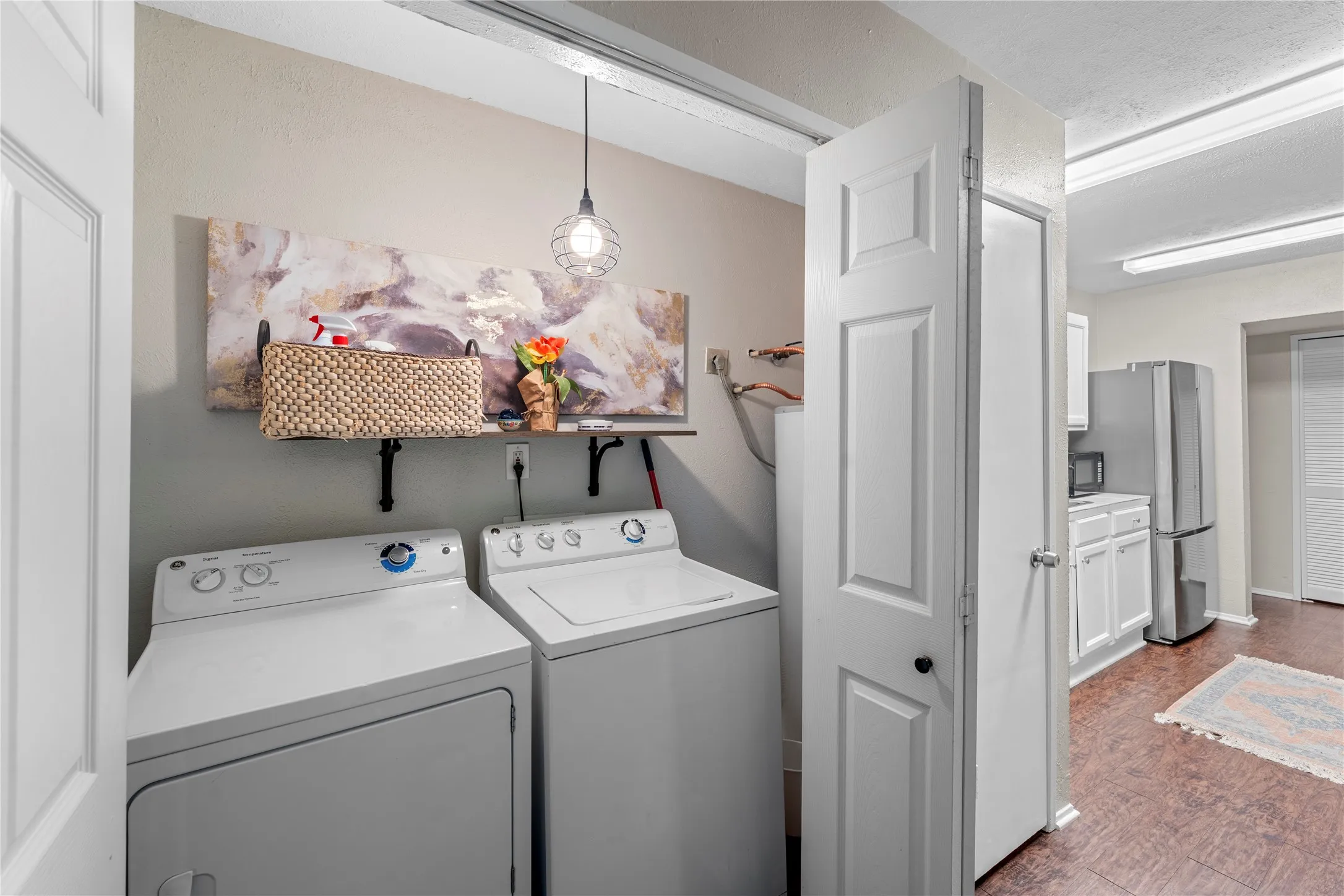Dedicated laundry area with a suspended pendant light fixture and wall-mounted shelving