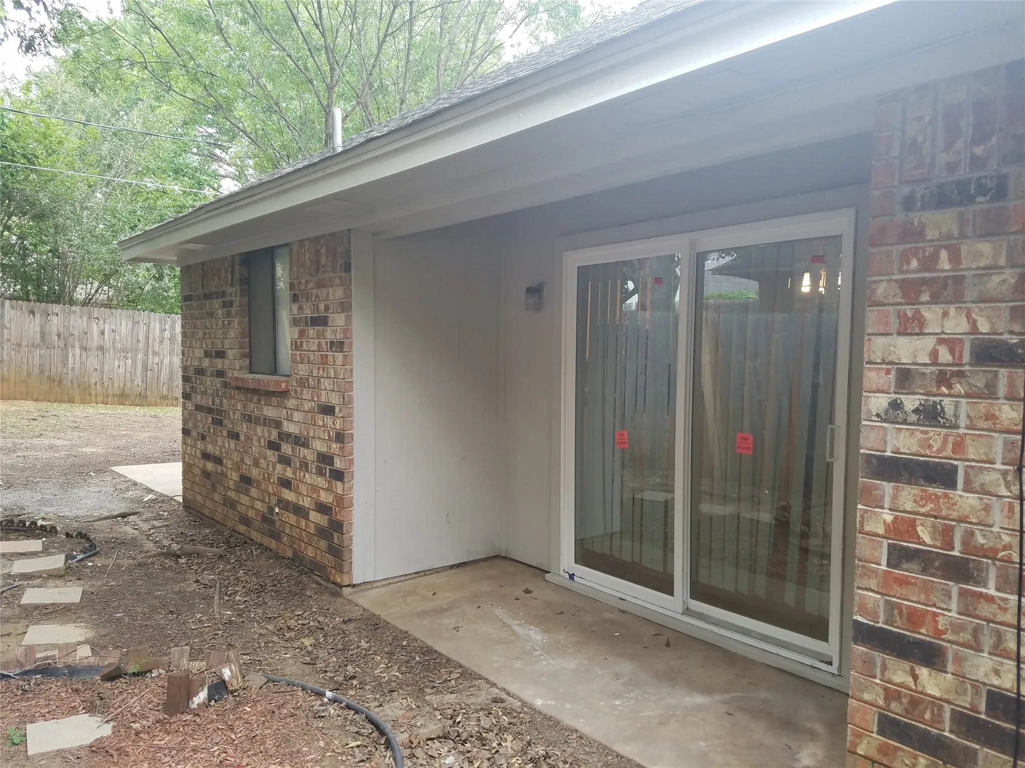 Brick exterior with a covered patio area and concrete walkway