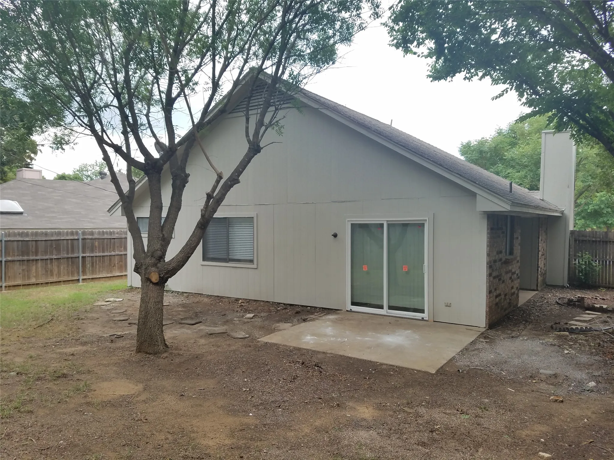 Rear exterior with a concrete patio, sliding glass door access, and a partial brick facade