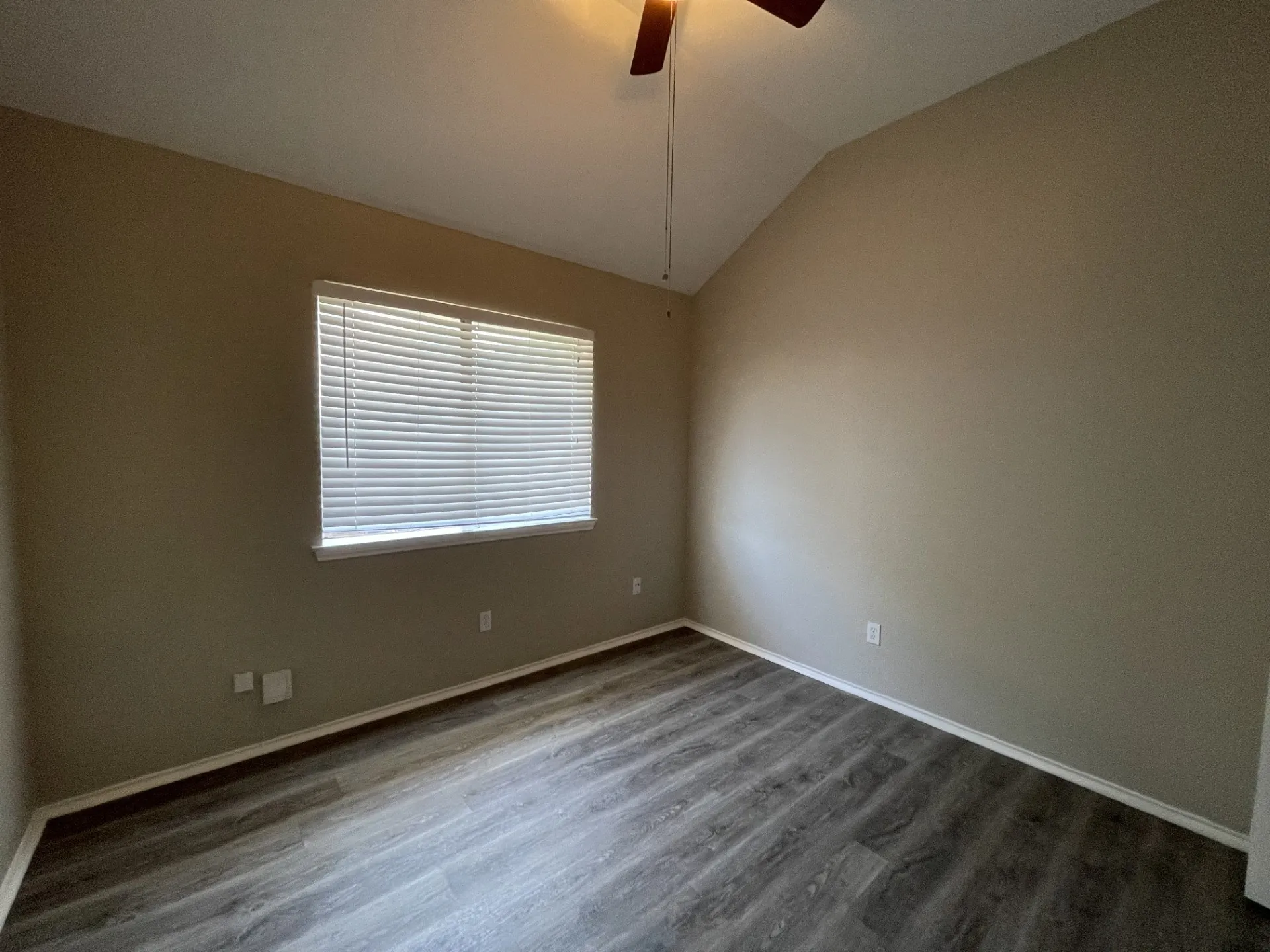 Vaulted ceiling, wood-finish flooring, ceiling fan, window with blinds
