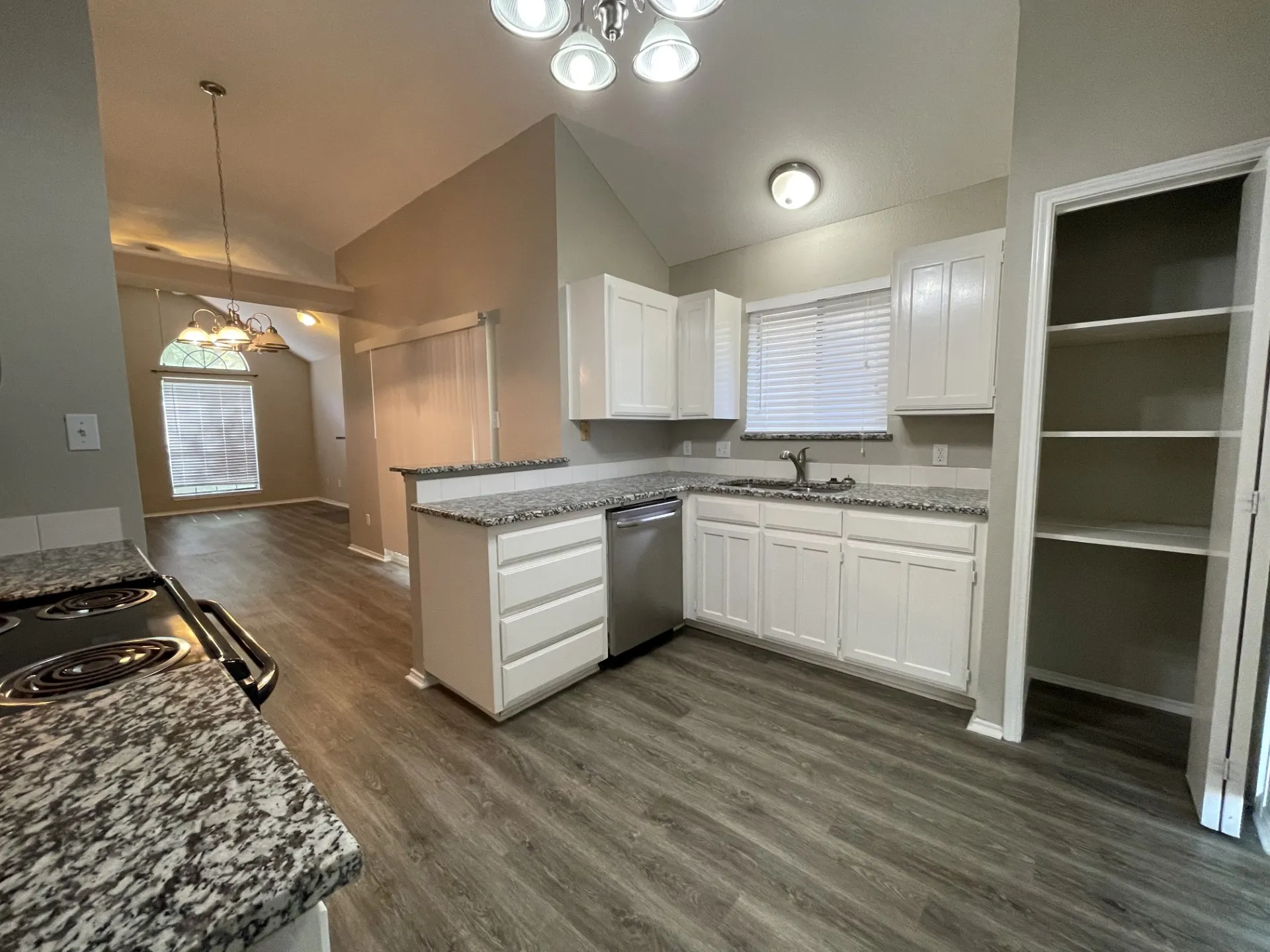Kitchen featuring wood-finish flooring, white cabinetry, granite-style countertops, and a built-in pantry