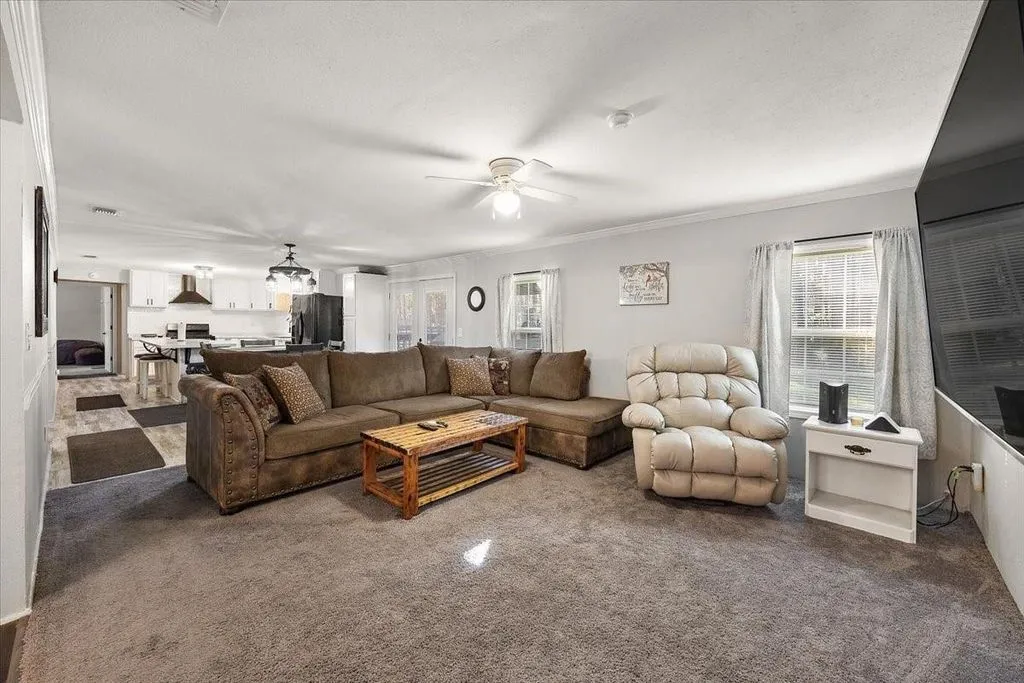 Spacious family living room featuring neutral carpet, ceiling fan, and generous room for sectional seating.