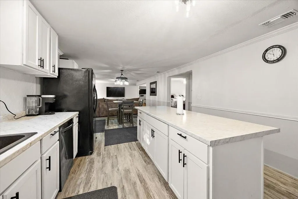 Broad view of the updated kitchen showcasing extensive counter space, island prep area, and ceiling fan fixture.