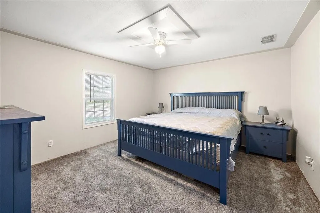 Third secondary bedroom with stylish navy bed frame, central light fixture, and bright window light.