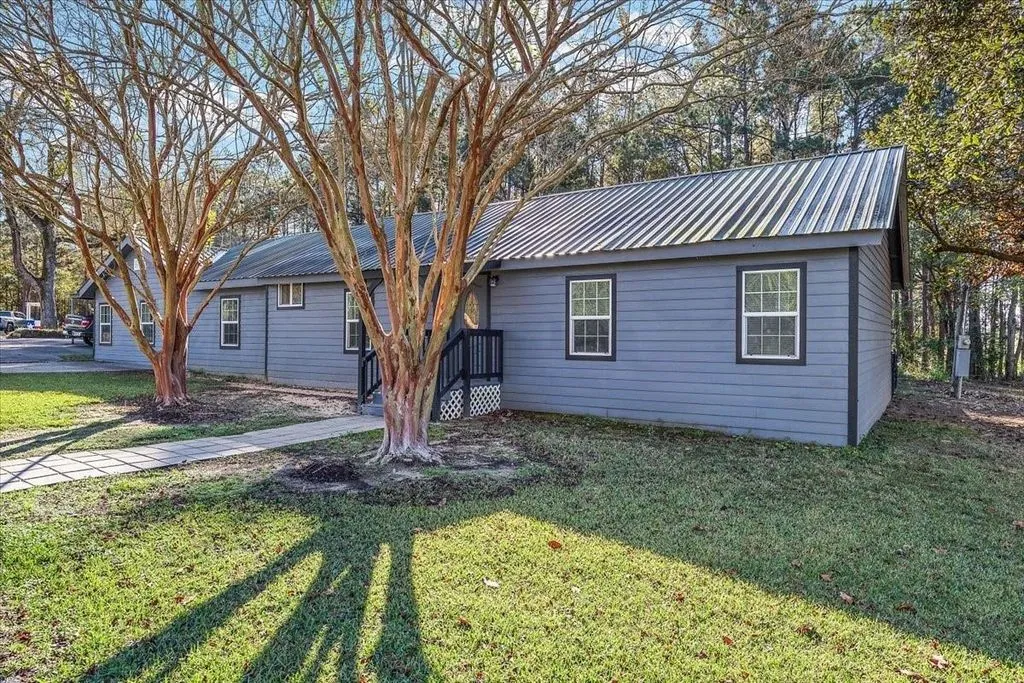 Angled front elevation showcasing the home profile, mature shade trees, and spacious yard space.