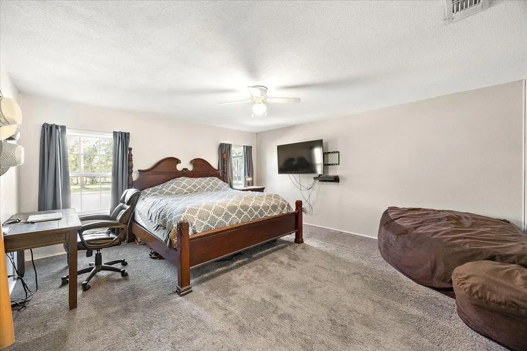 Secondary bedroom featuring carpeted flooring, window drapes, ceiling fan, and generous floor space.
