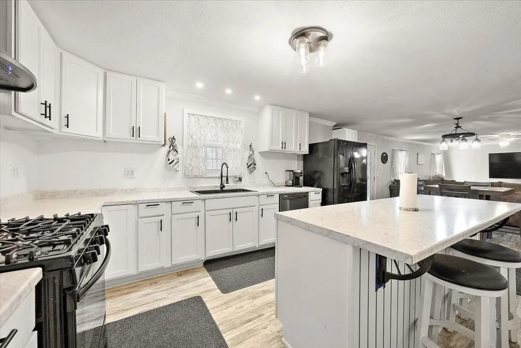 Kitchen workspace highlighting stainless steel oven range, black hood vent, and bright open design.