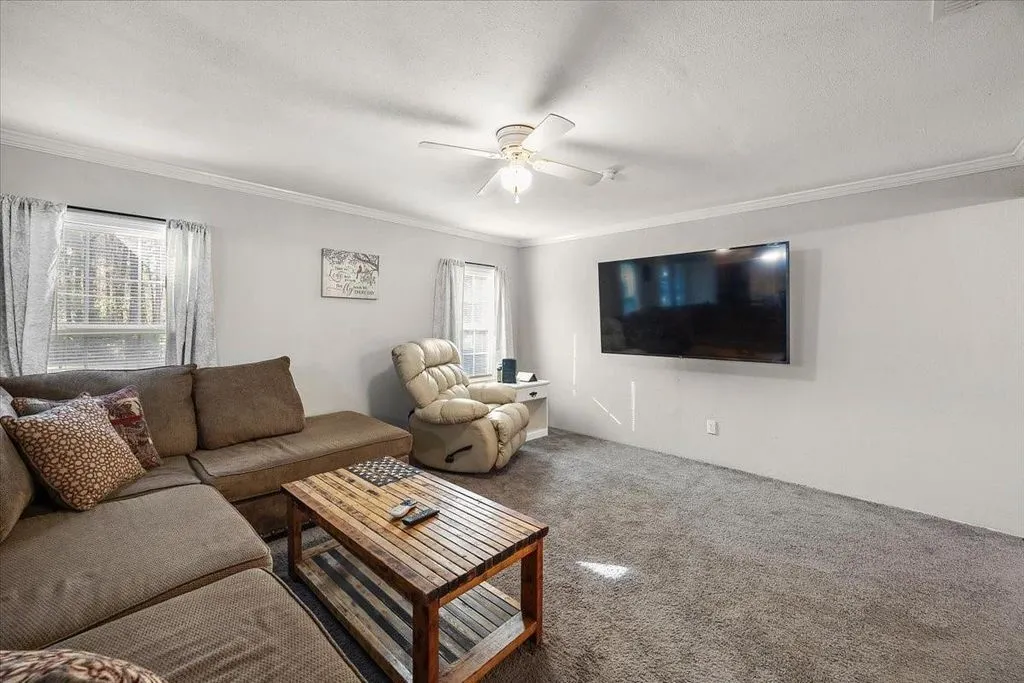Living room alternate angle highlighting wall-mounted TV setup, soft wall tones, and open space.