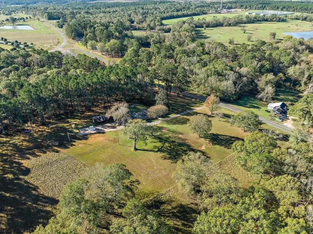 High-altitude aerial drone view capturing the entire property acreage, tree canopy, and countryside setting.