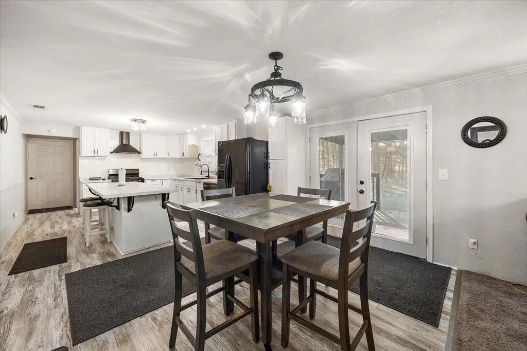 Dedicated dining area adjacent to the kitchen with overhead chandelier lighting and window view.