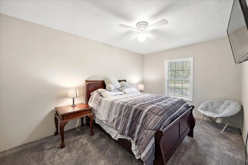 Fourth guest bedroom equipped with ceiling fan, neutral tones, and carpet flooring.