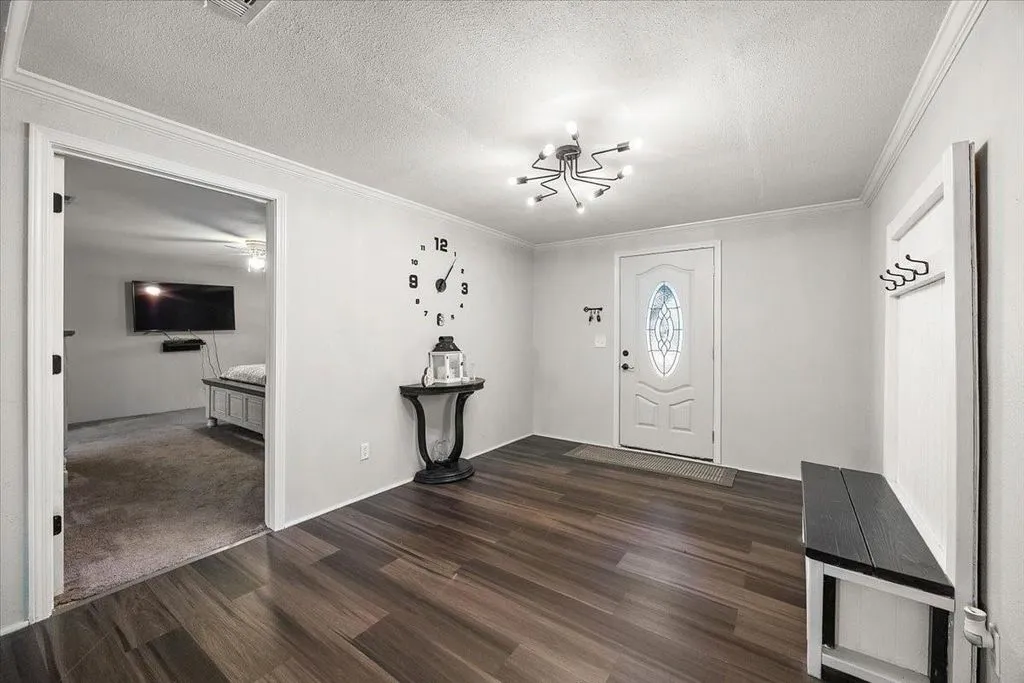 Welcoming interior entry foyer featuring dark wood-look flooring, light grey walls, and modern lighting fixture.