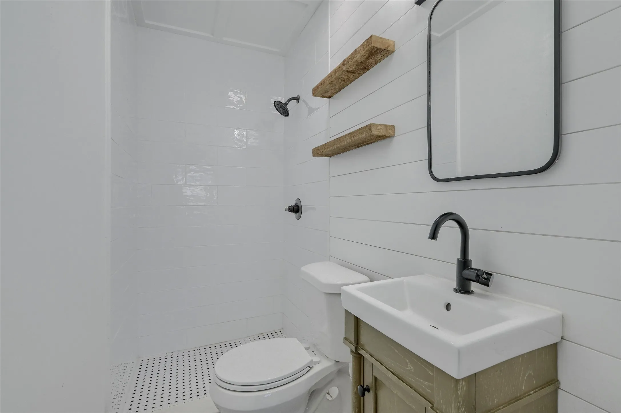 Bathroom featuring toilet, vanity, and a tile shower