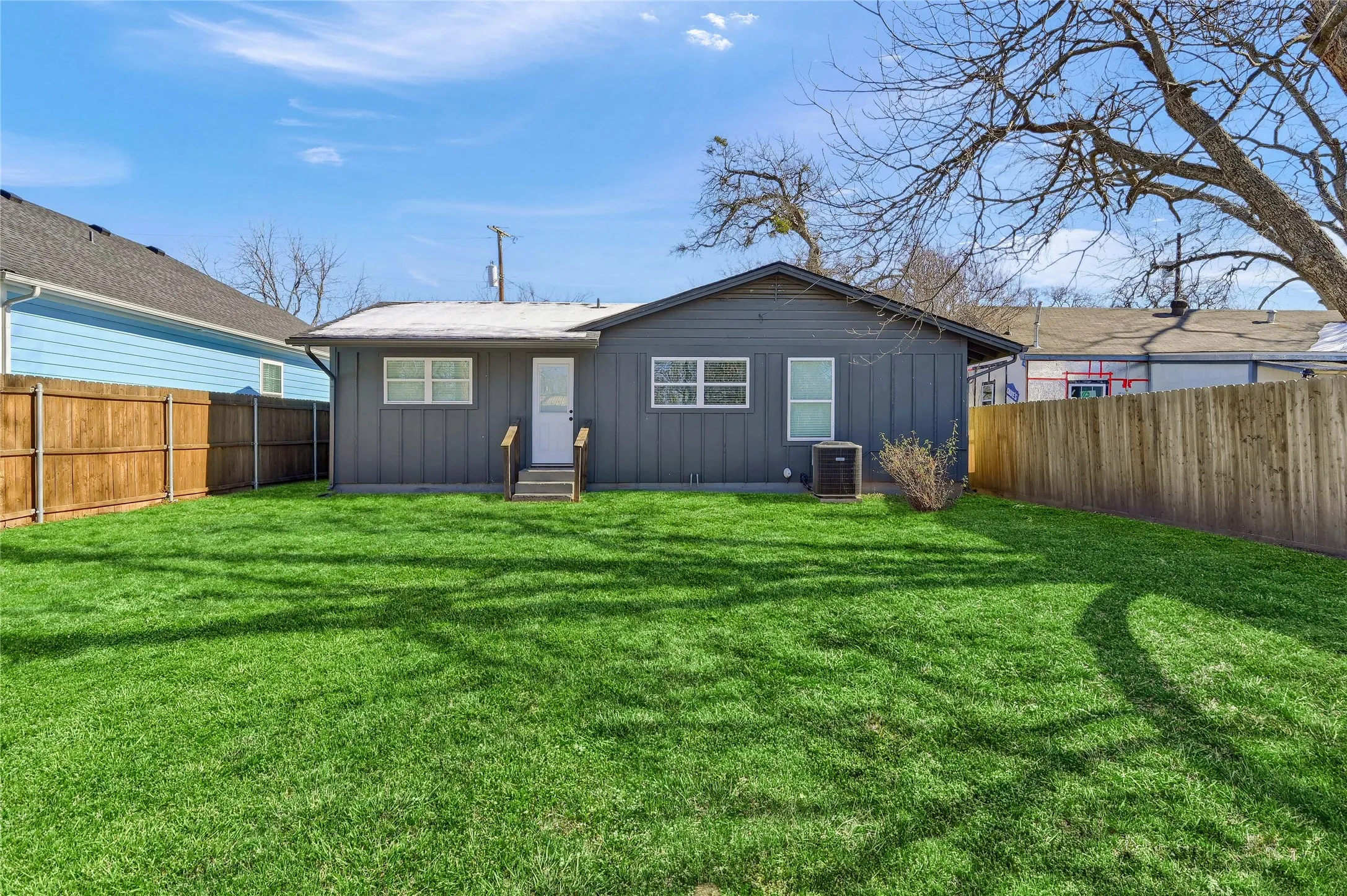 Back of house featuring a lawn and central AC