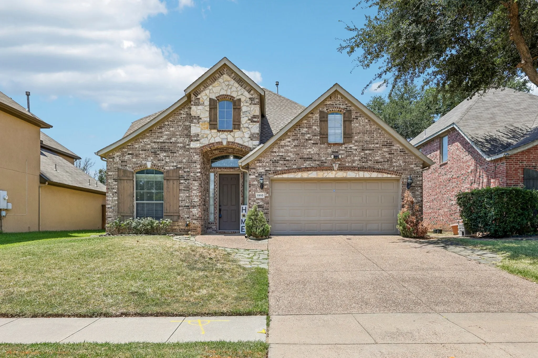 Brick and stone facade residence featuring a covered entry, arched window above the front door, and decorative window shutters