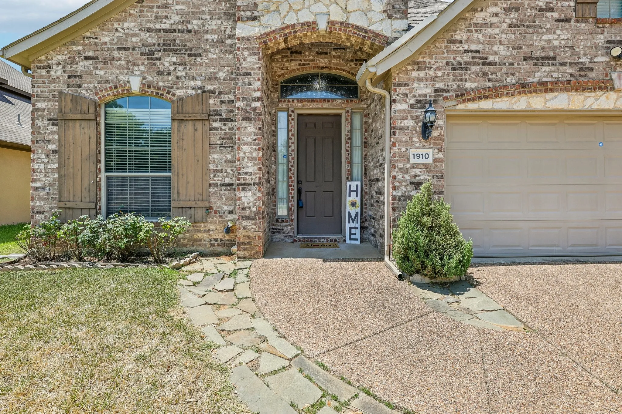 Brick and stone exterior featuring an arched entryway and an attached garage