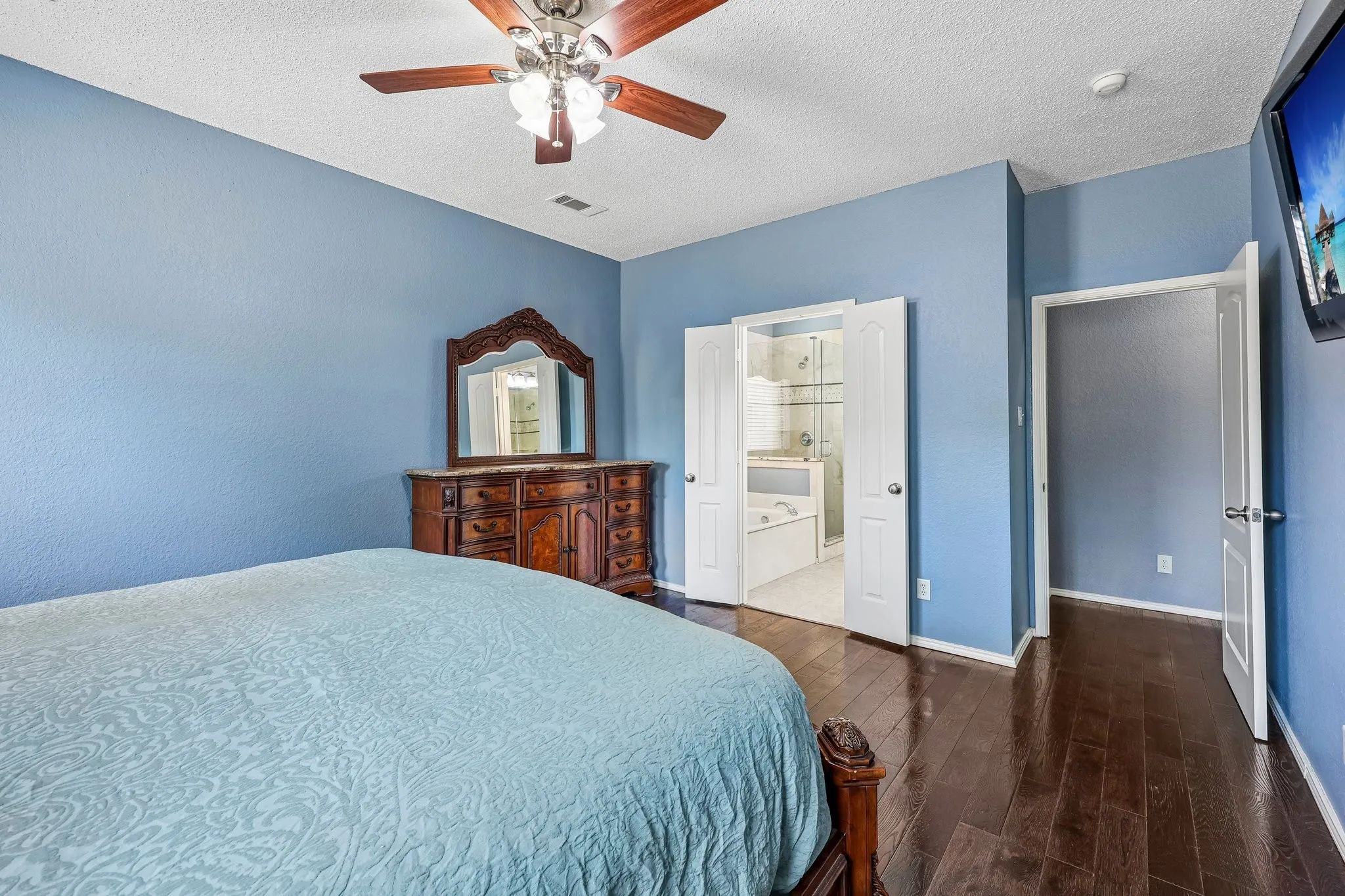 Spacious room with dark wood-finish flooring and light blue walls