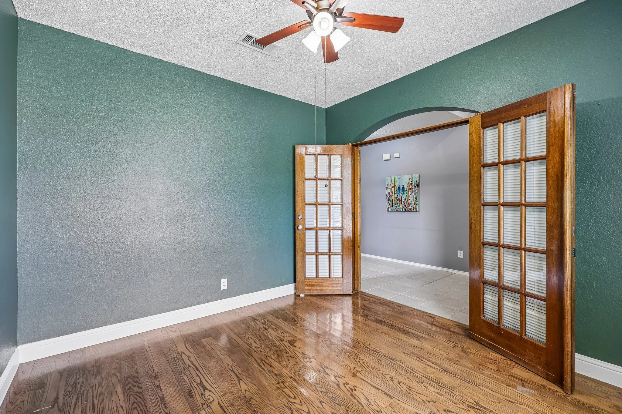 Room featuring wood-finish flooring, dark green walls, and white baseboards