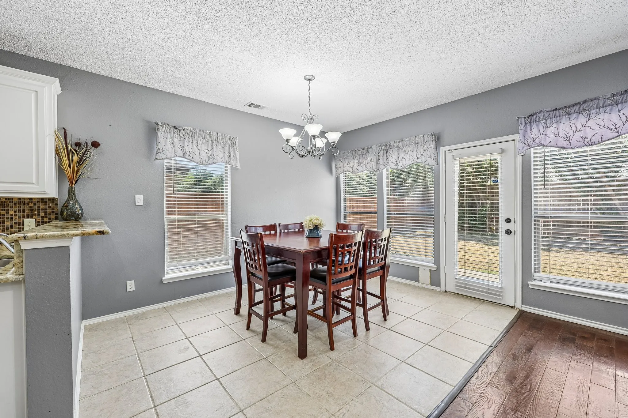 Light-filled dining area featuring tile flooring, multiple windows, and a glass-paneled door